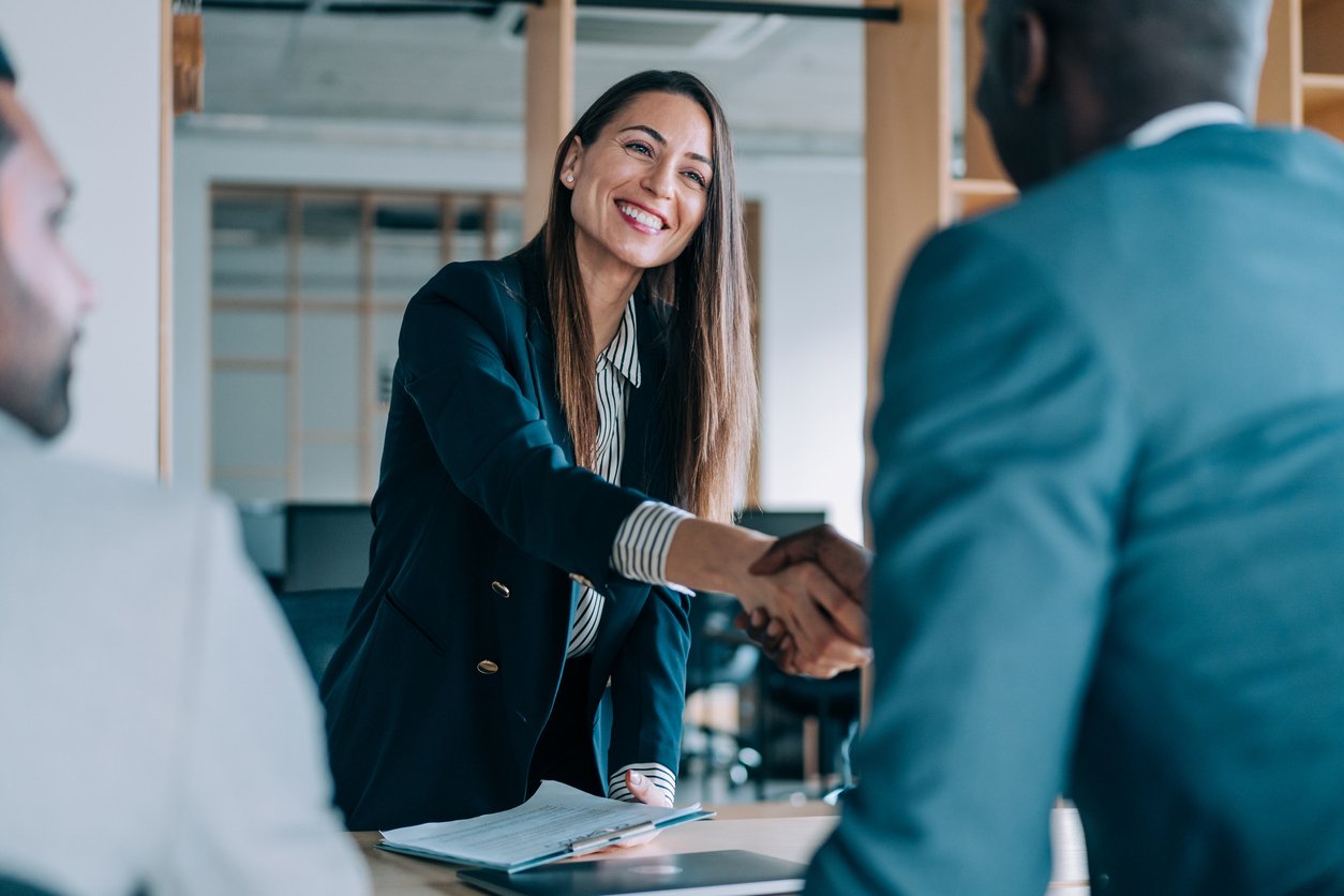 Two people shaking hands across a desk