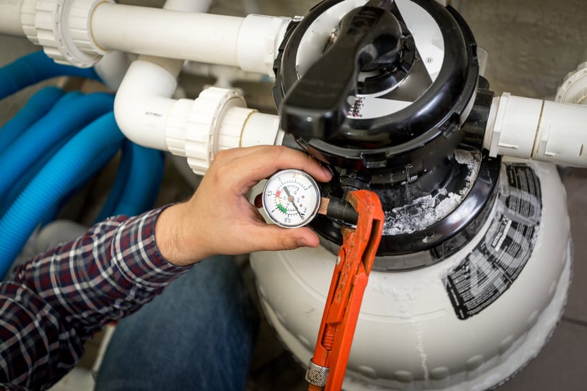 A hand holding a gauge on a fuel tank