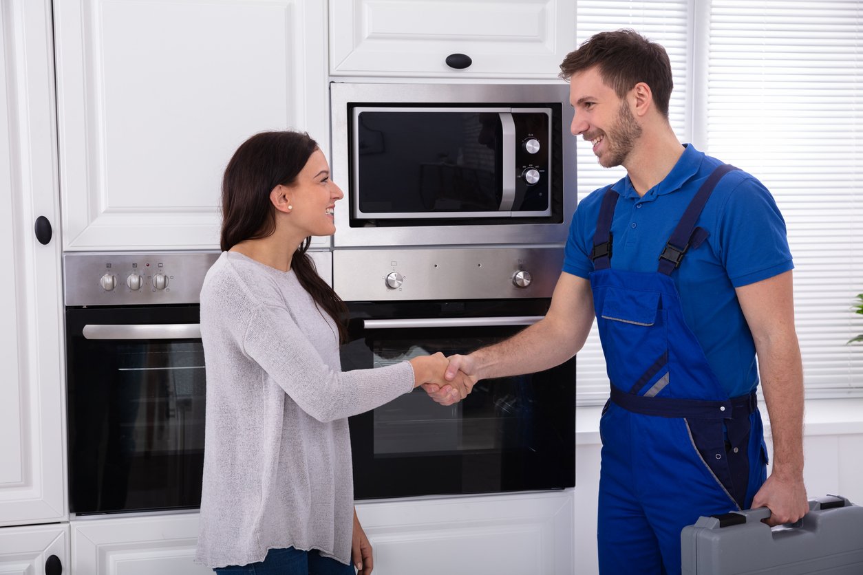 Smiling appliance repair tech shaking hands with happy customer