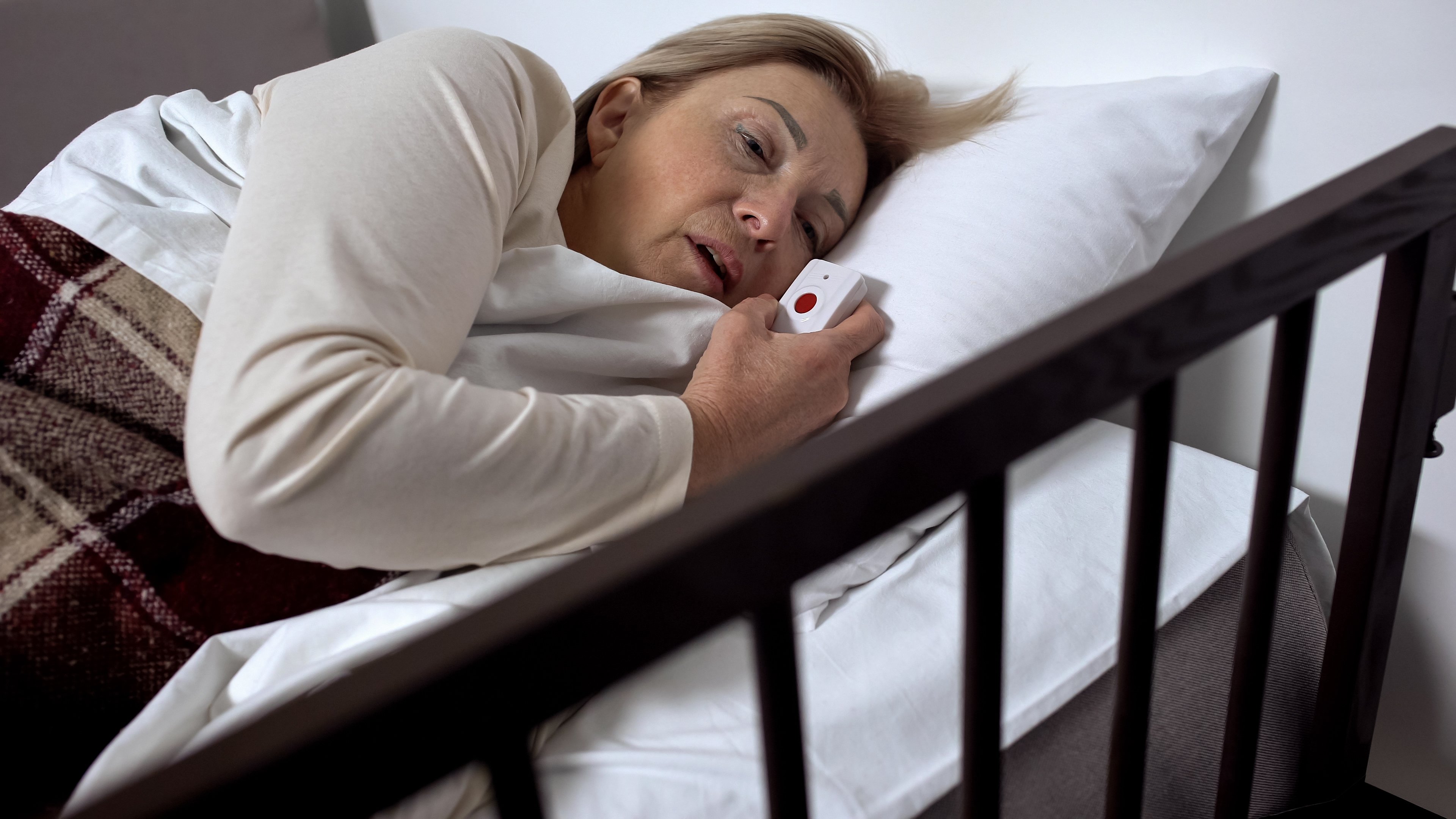 Woman lying in hospital bed holding call button