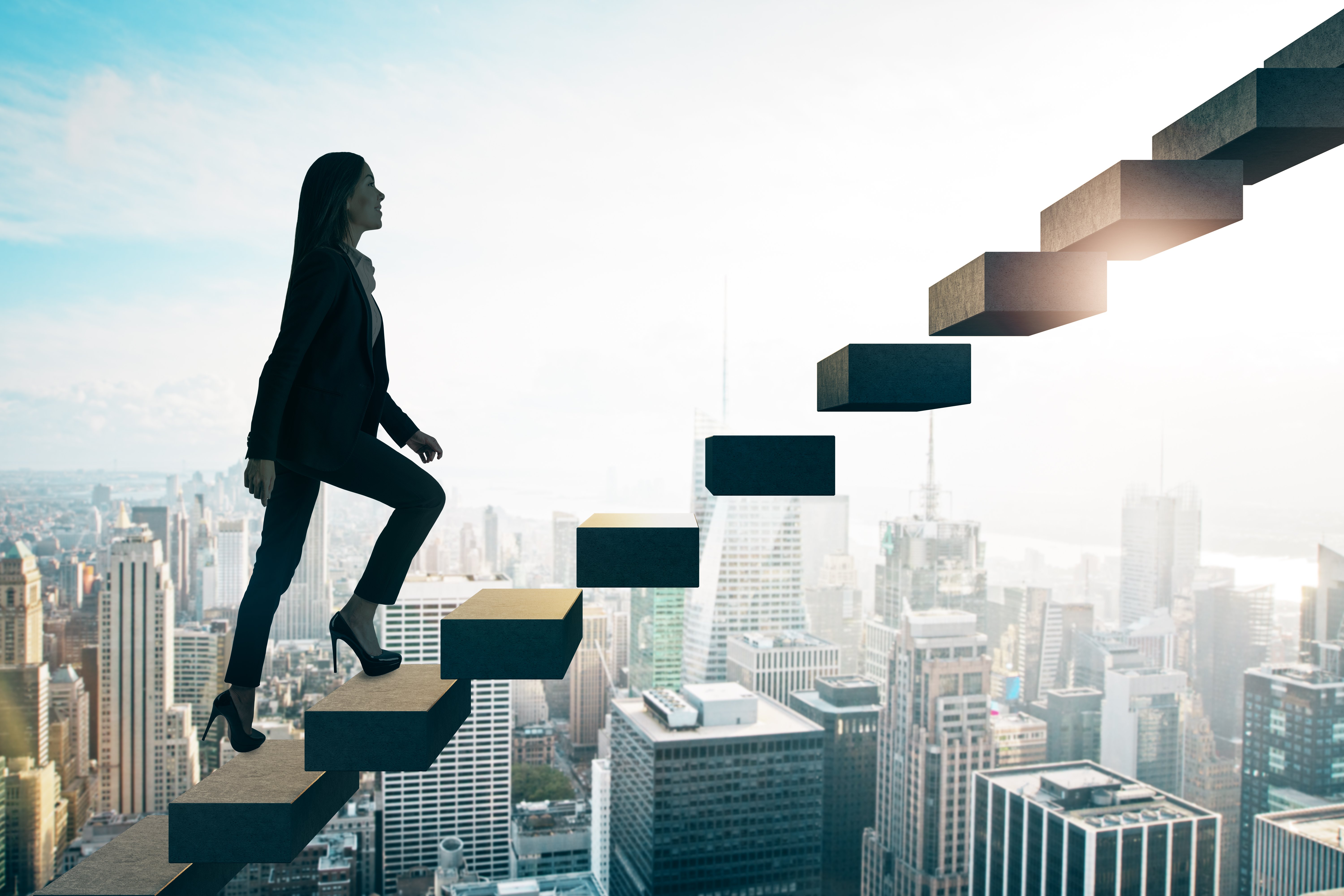 Businesswoman going up some stairs on sunny city background