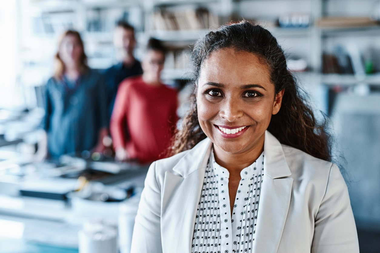 Smiling businesswoman with three members of her team in the background