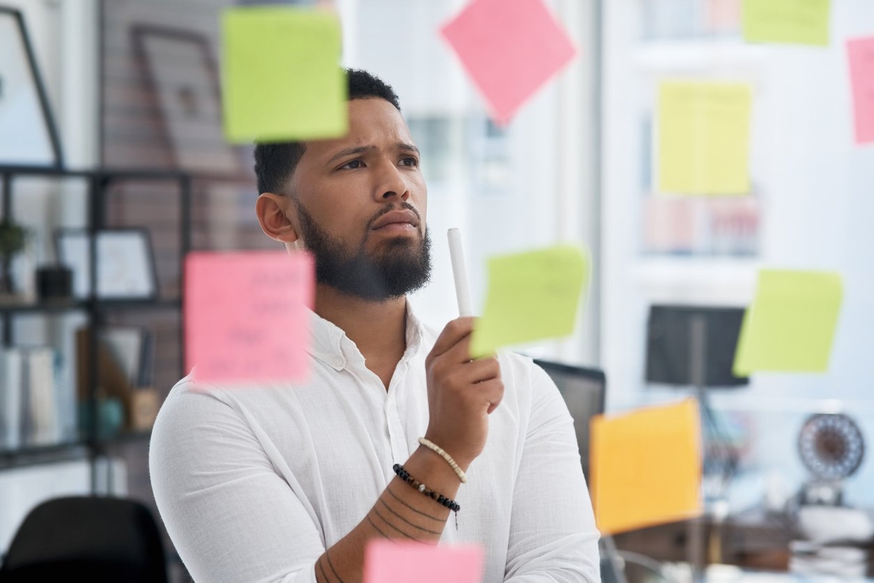 Young businessman brainstorming with sticky notes on a glass wall