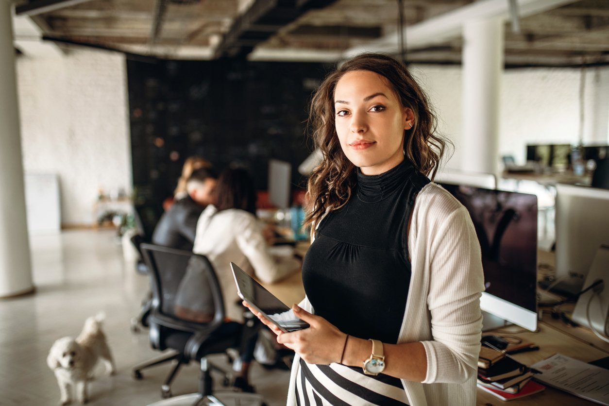 Young businesswoman standing in office holding tablet