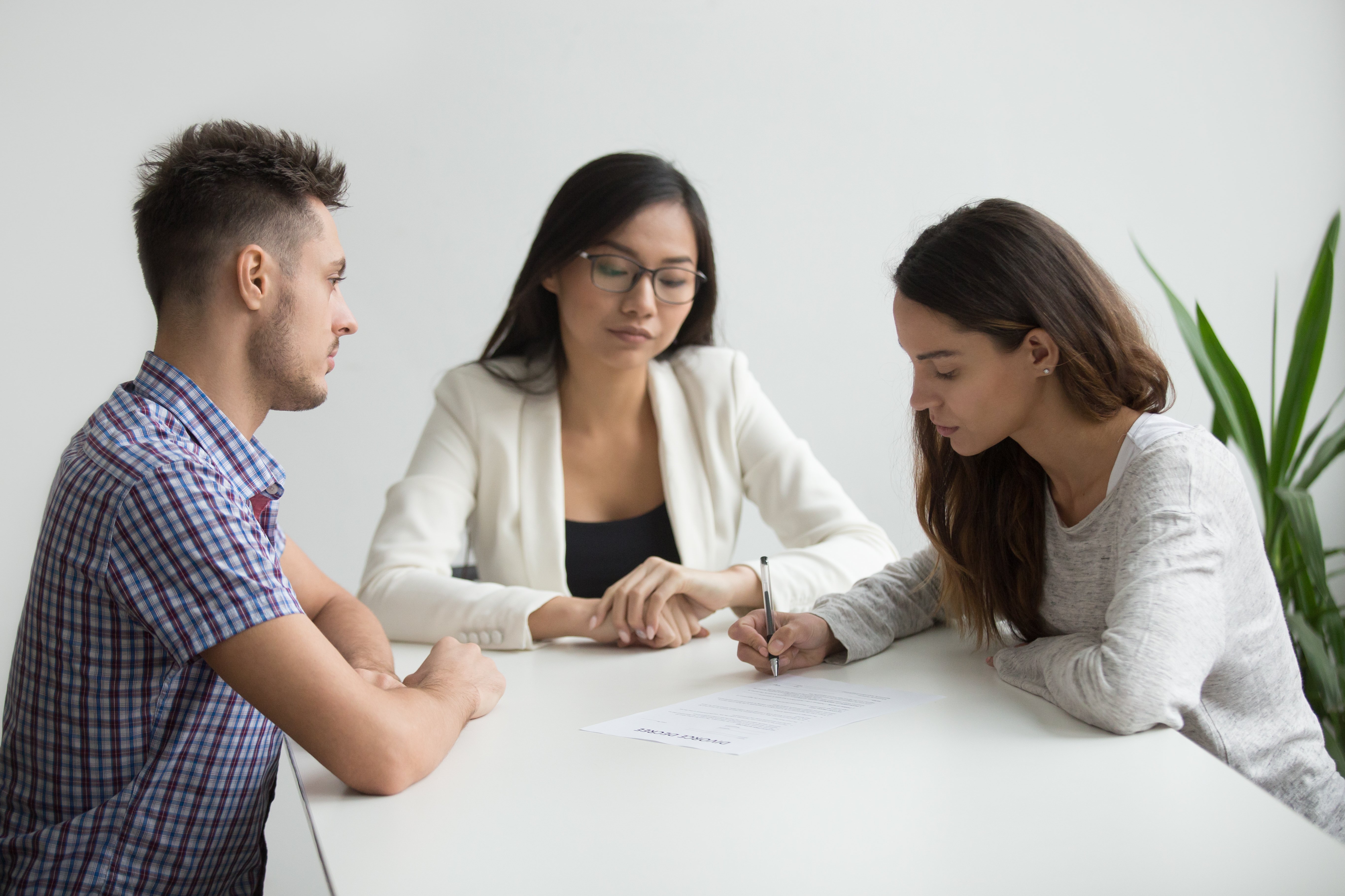 A couple signing an agreement in front of a mediator