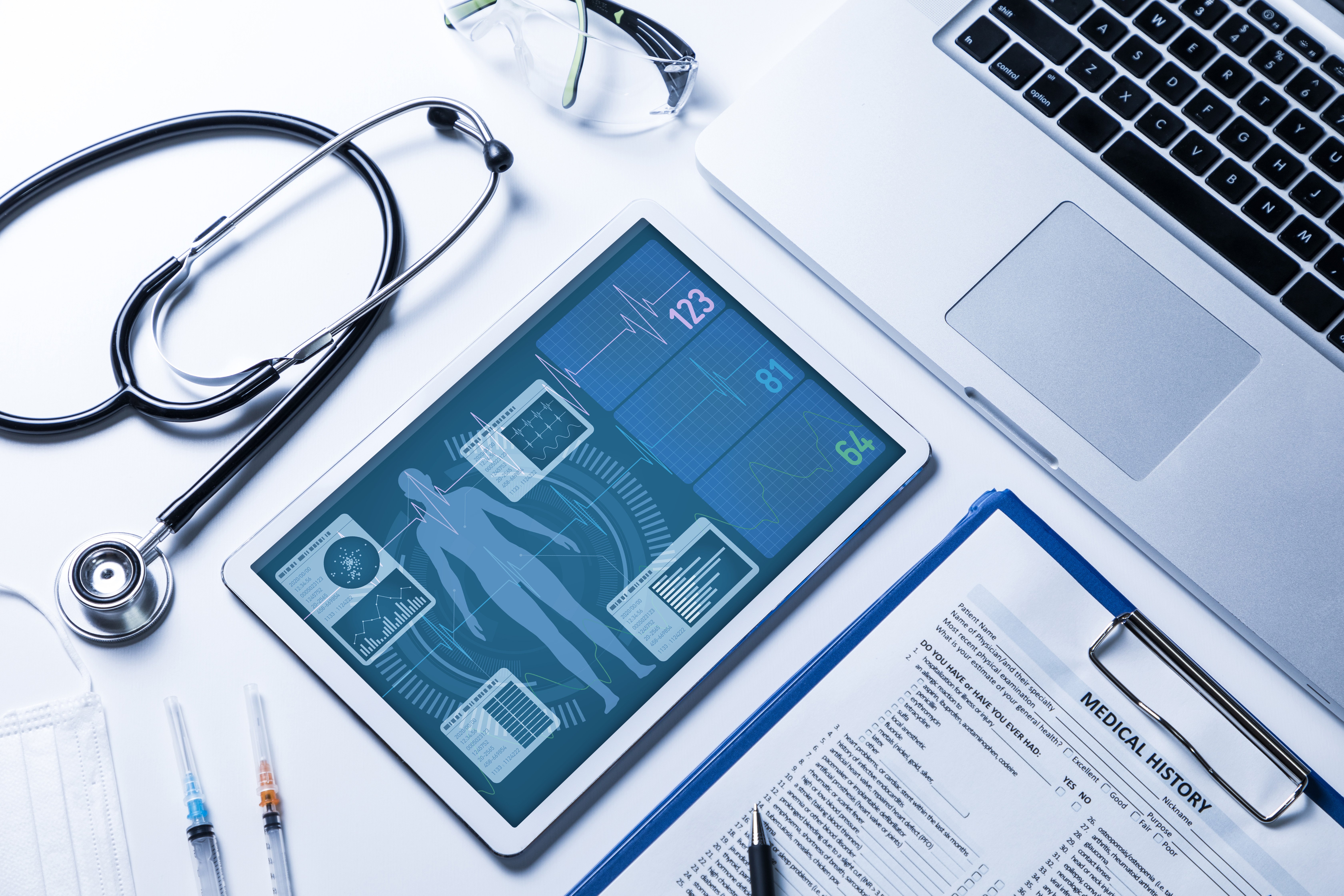 Tablet showing vital signs next to laptop and stethoscope