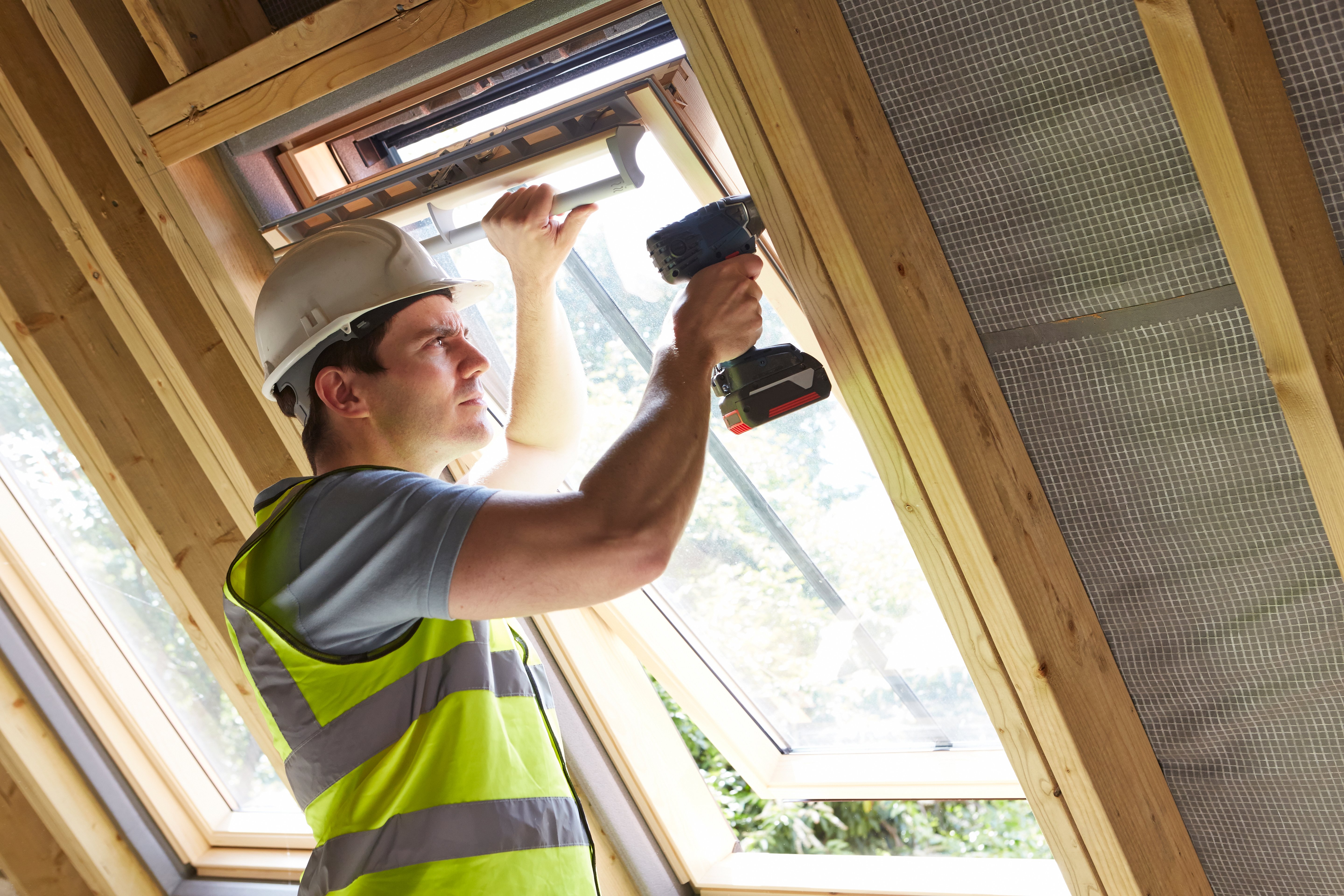 Carpenter using drill to install window
