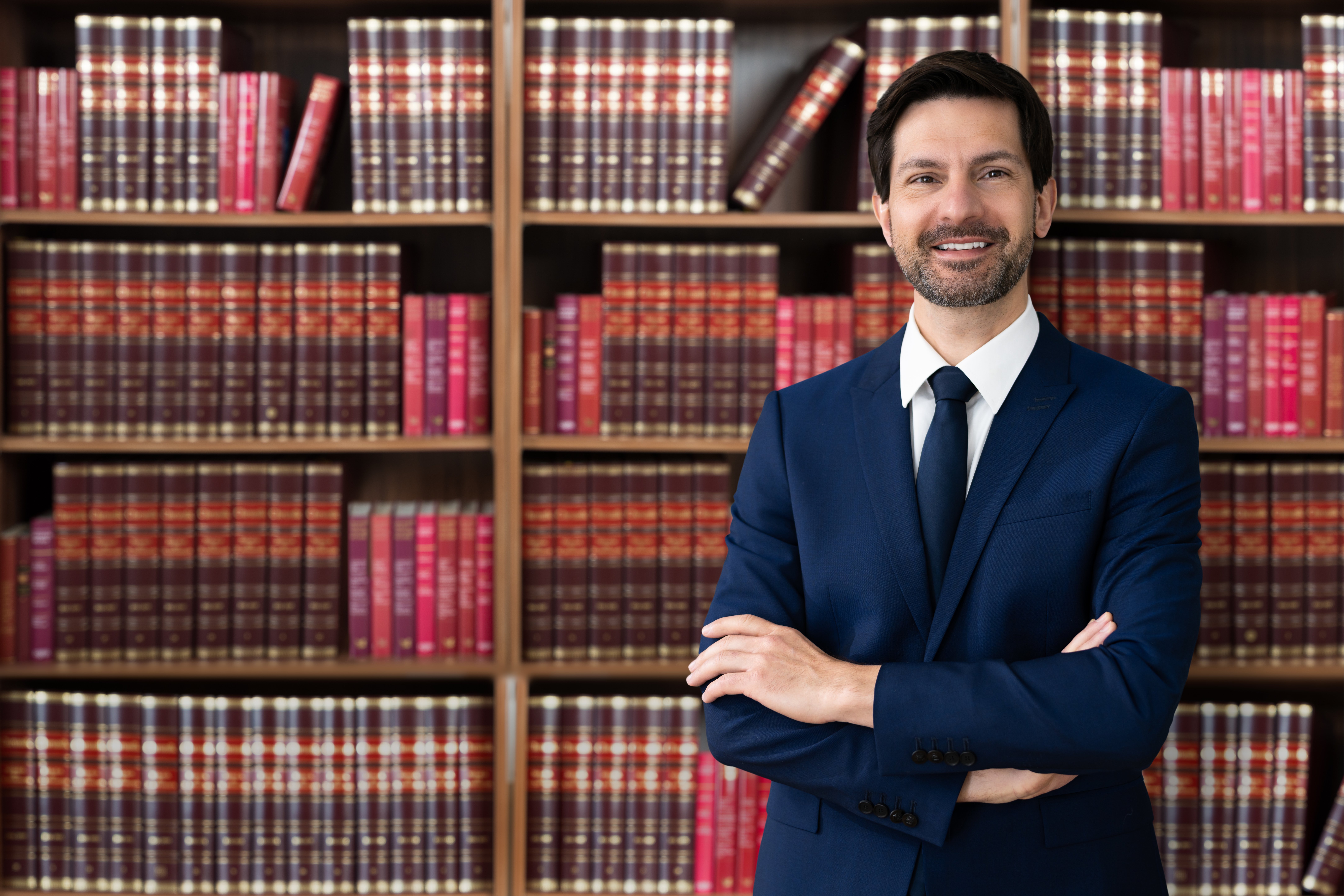 Law clerk standing with arms crossed in front of bookcases