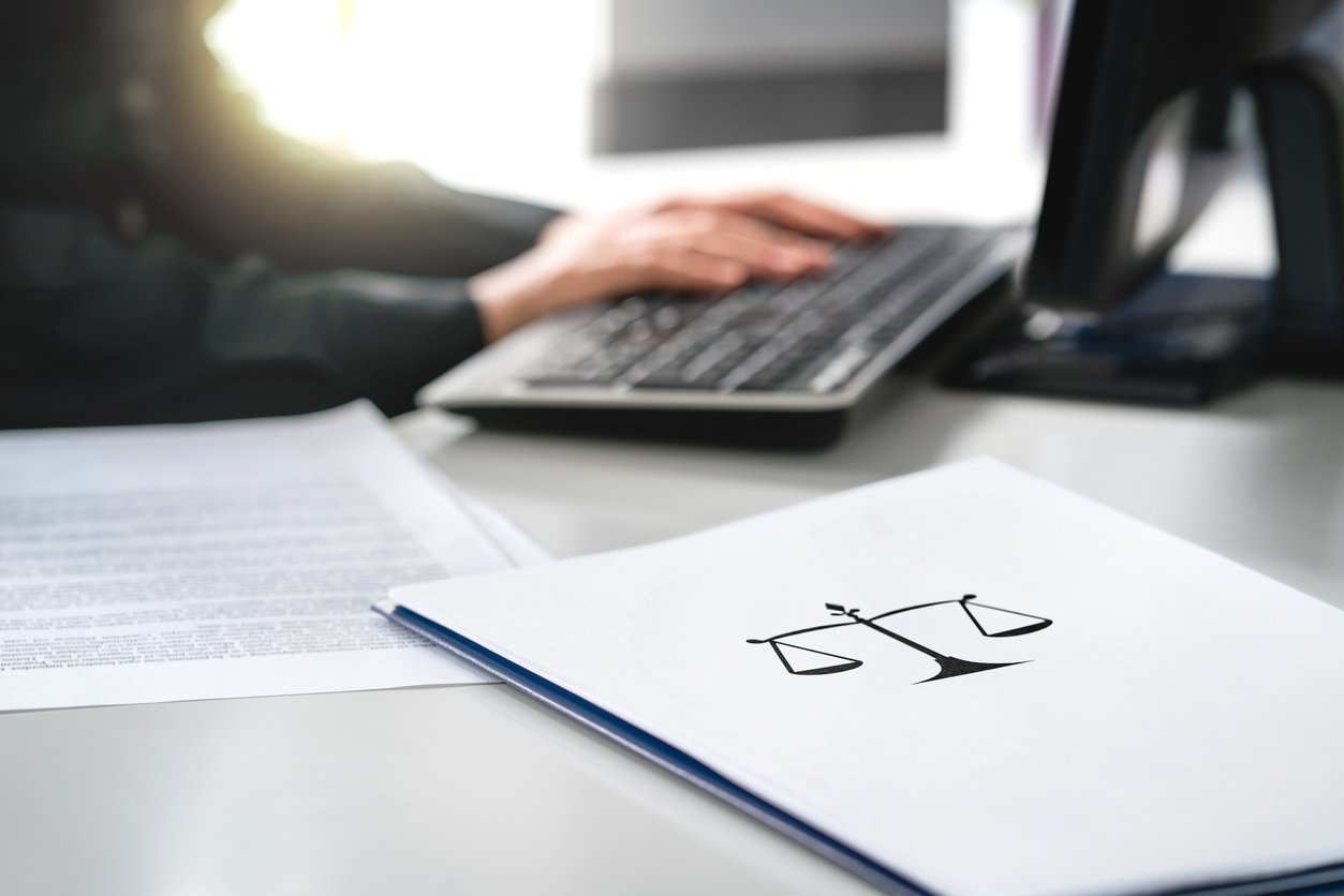 Legal assistant at computer with documents in the foreground