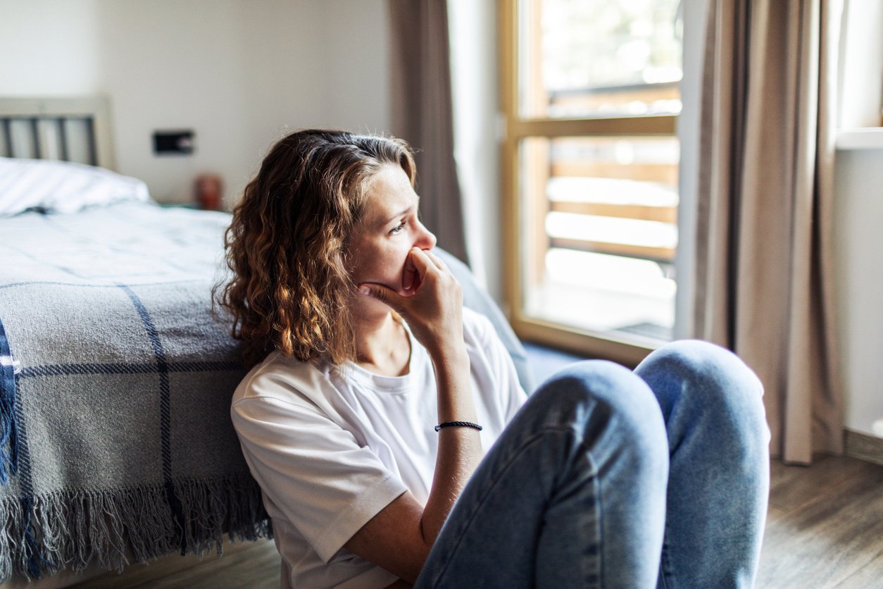 Young woman with depression sitting at home alone