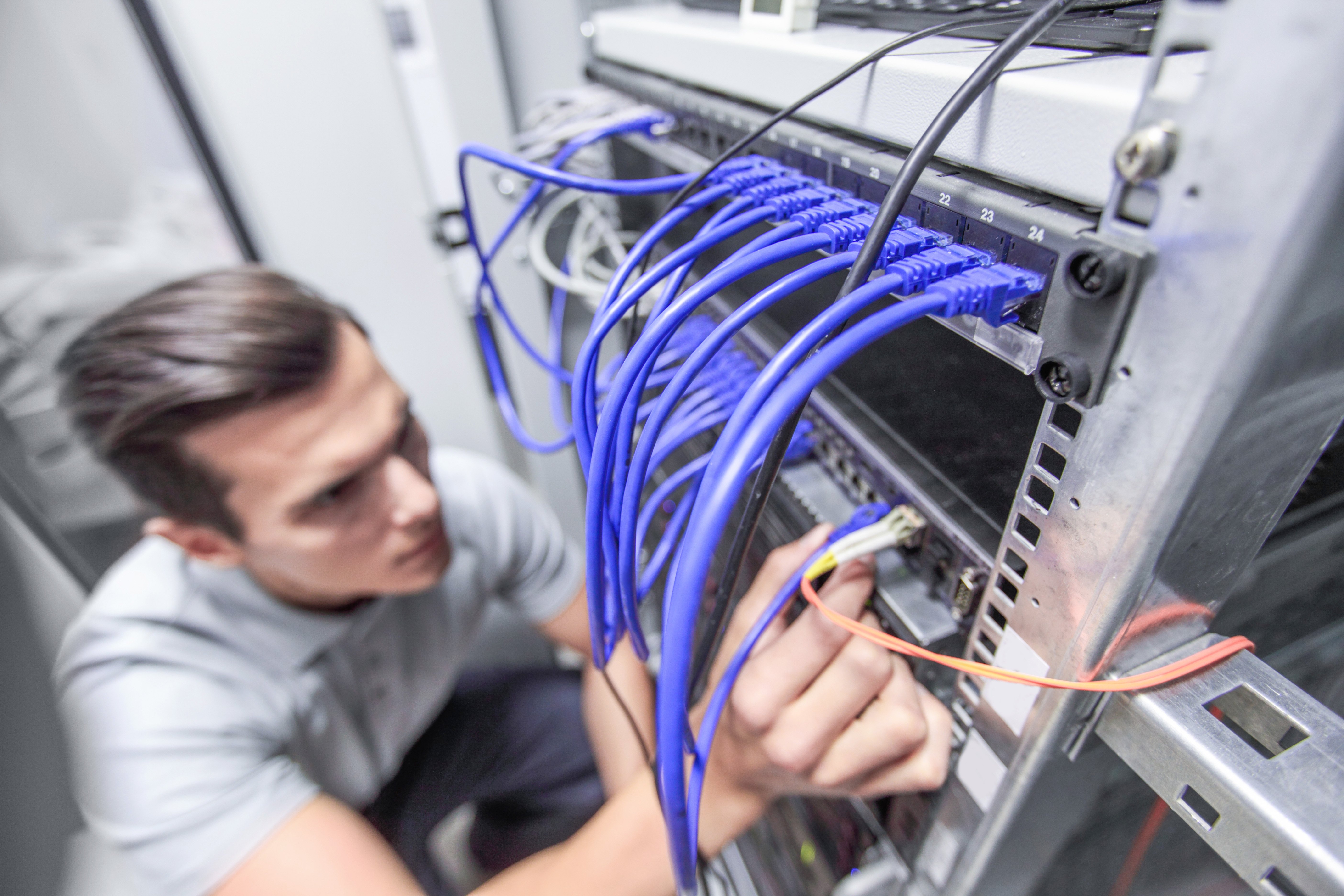 Network technician connecting cables in server room