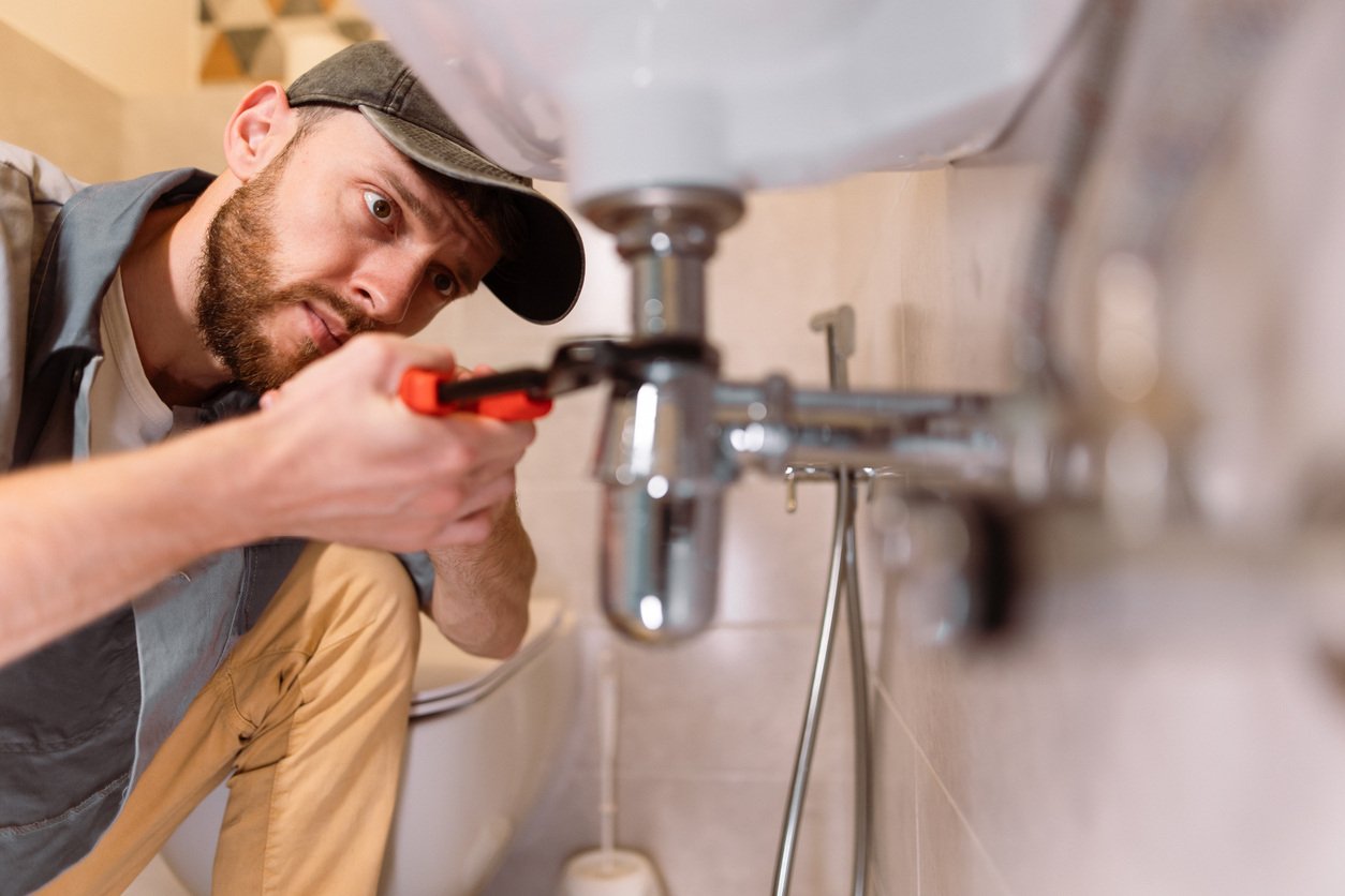 A plumber fixing a leak under a sink