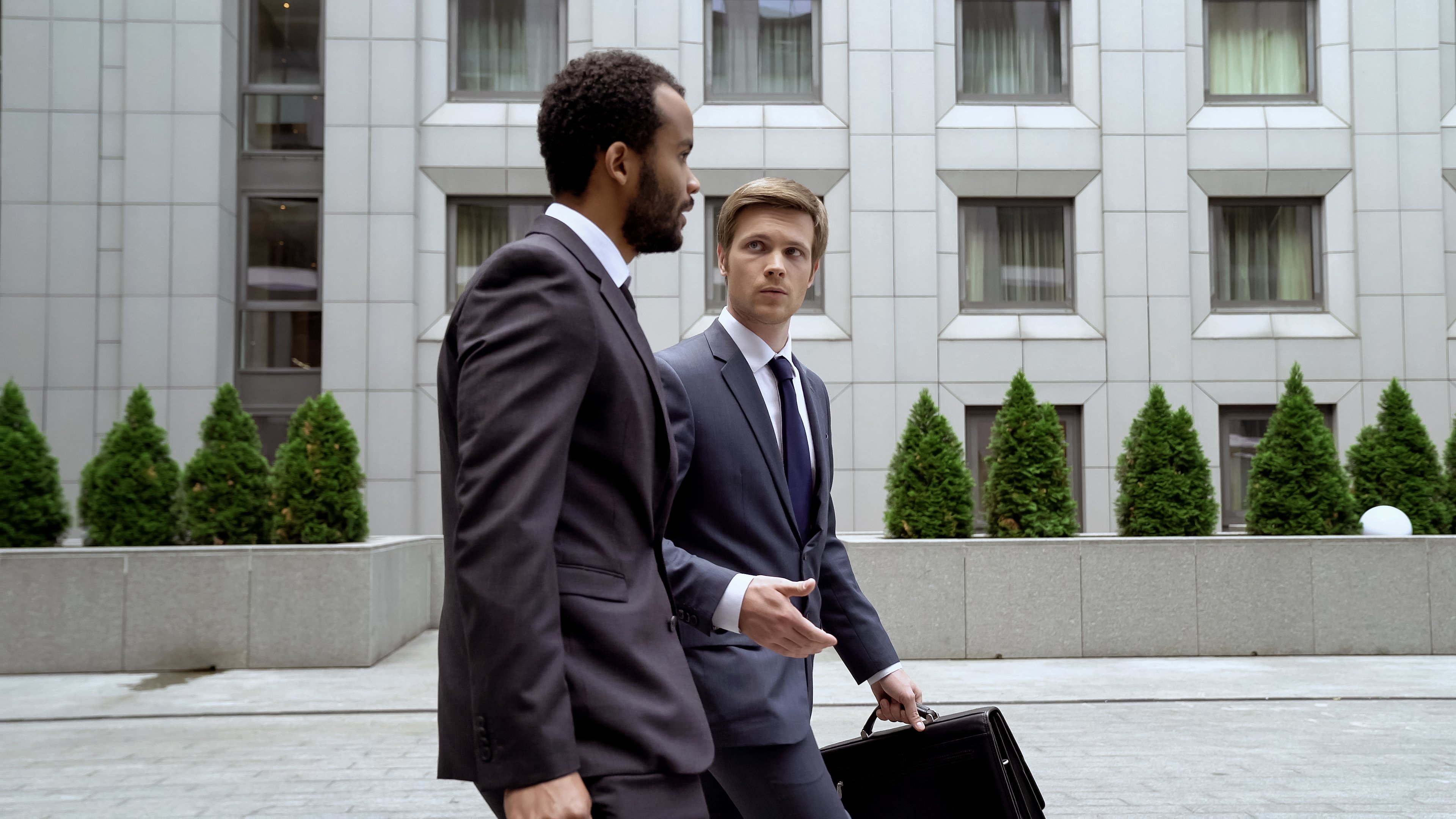 Two men in suits walking outside a large building