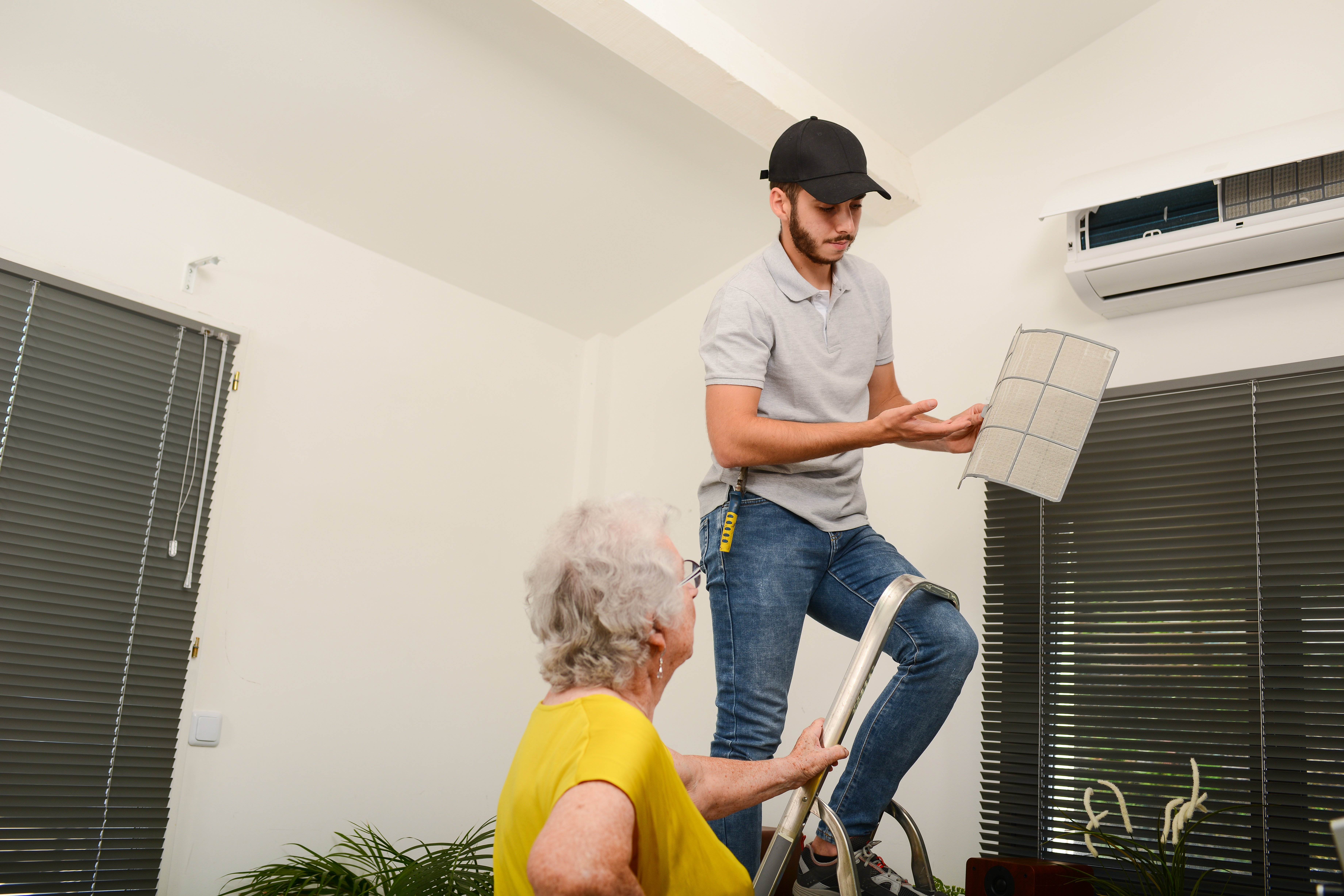 HVAC technician on ladder in customer home