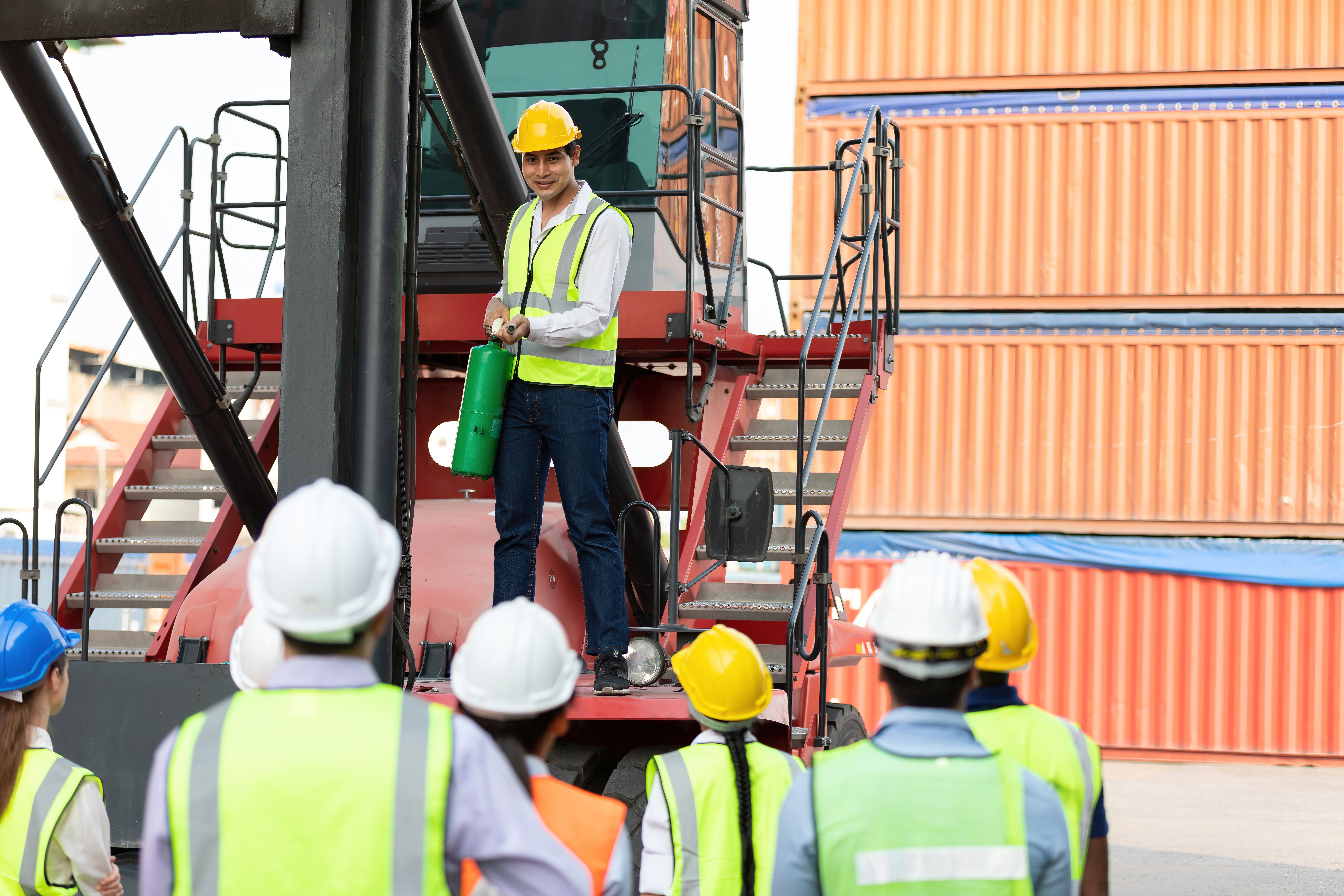 Safety officer demonstrating the use of a fire extinguisher to group of warehouse workers