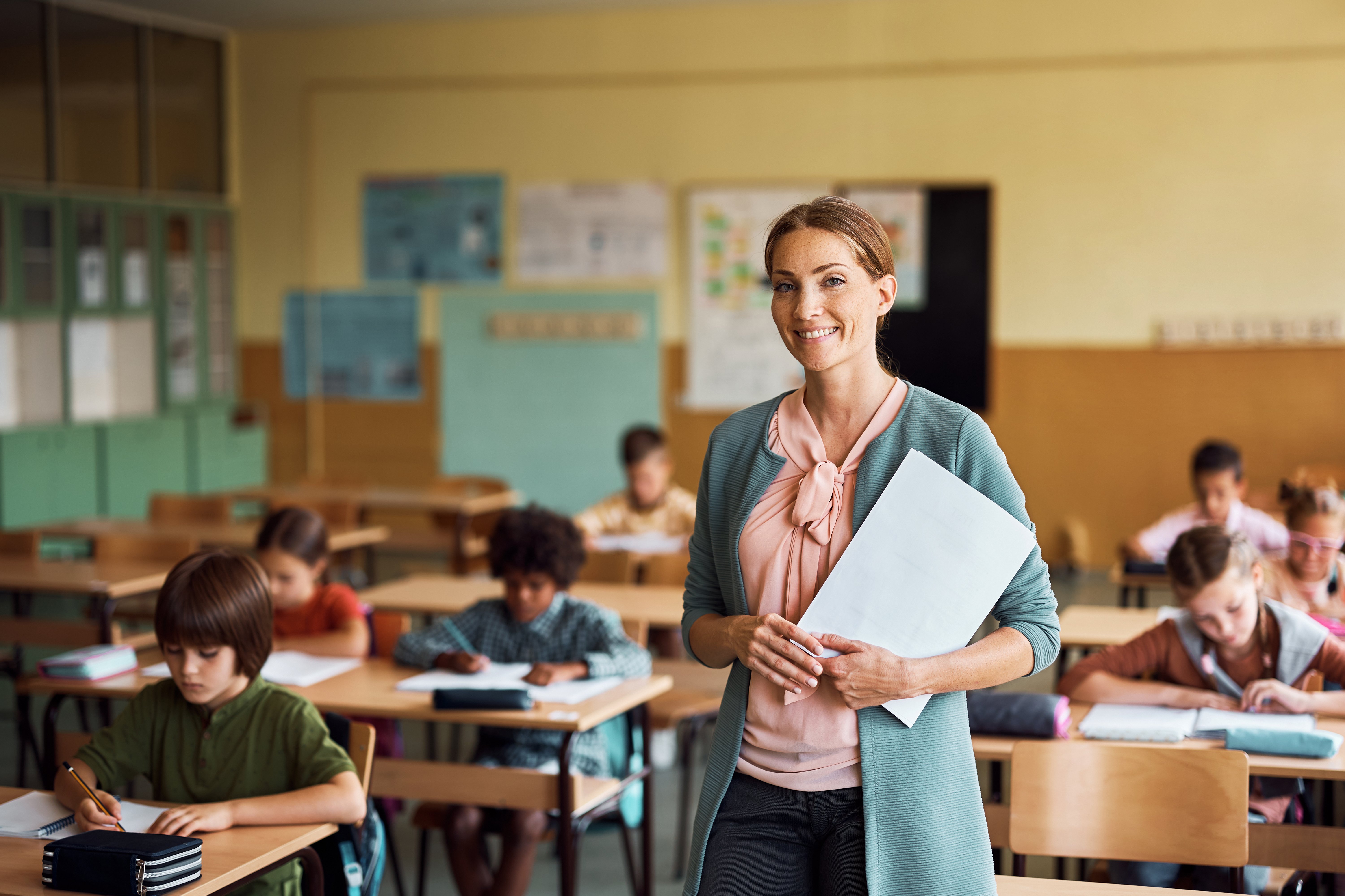 Elementary school teacher standing in classroom smiling at camera