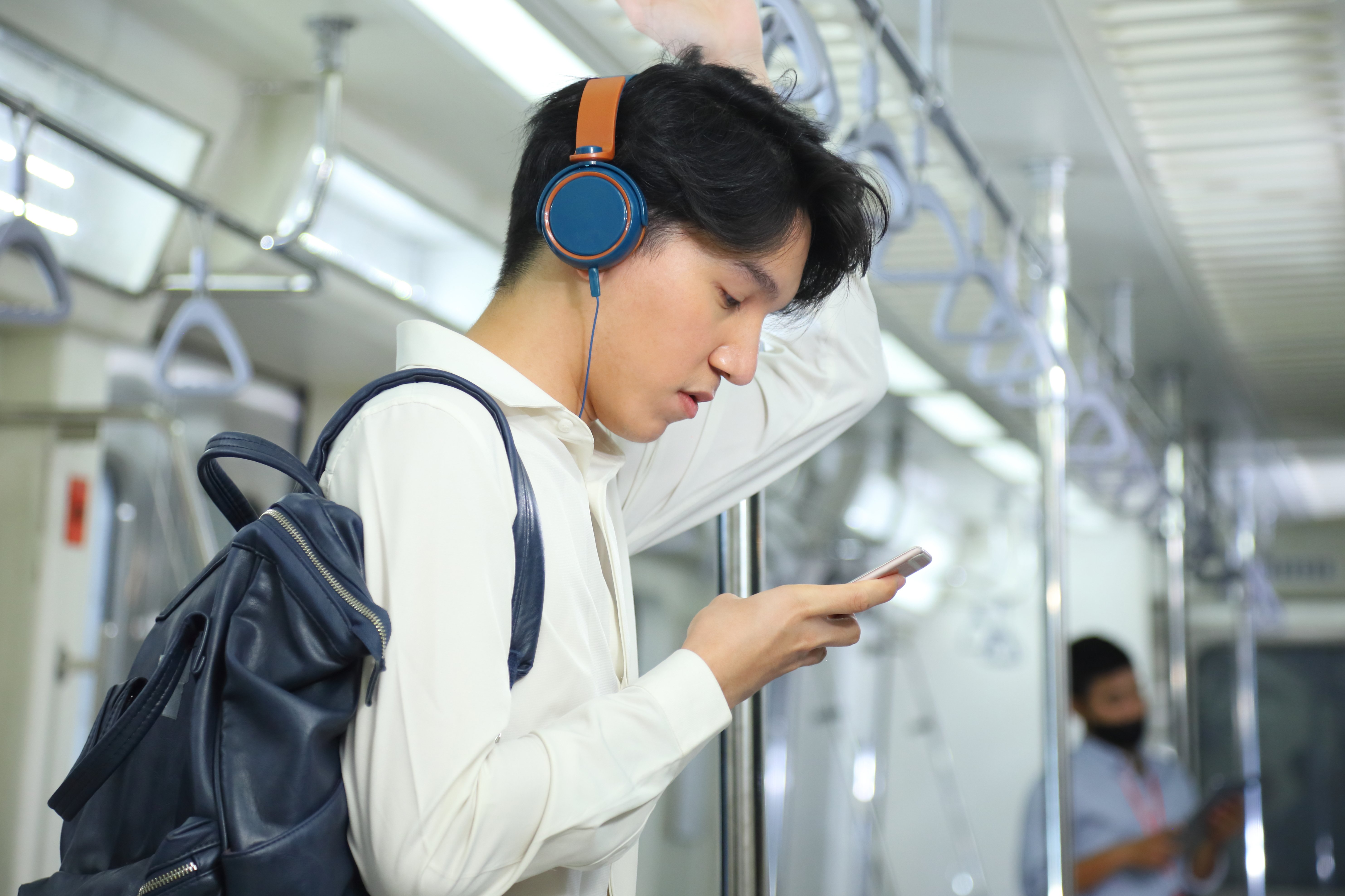 Étudiant dans le métro portant casque d’écoute regardant téléphone