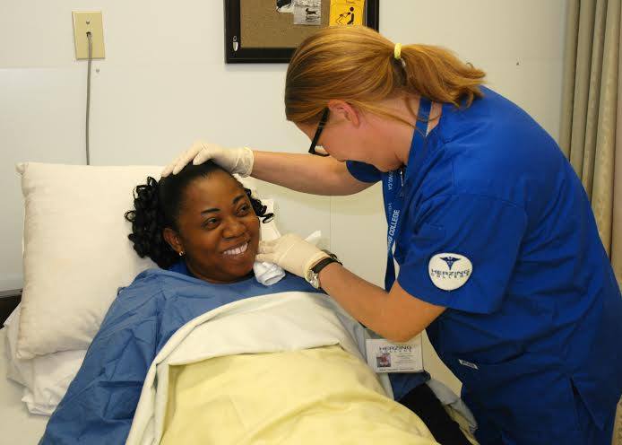 A health care aide student from Herzing College practices patient care procedures