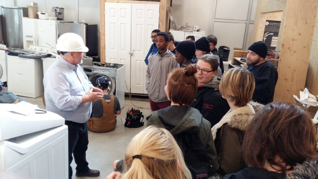 A Herzing College instructor leads a campus tour and explains appliance repair programs