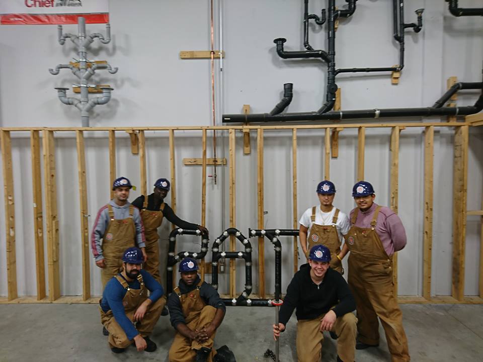 Herzing plumbing students posing in workshop