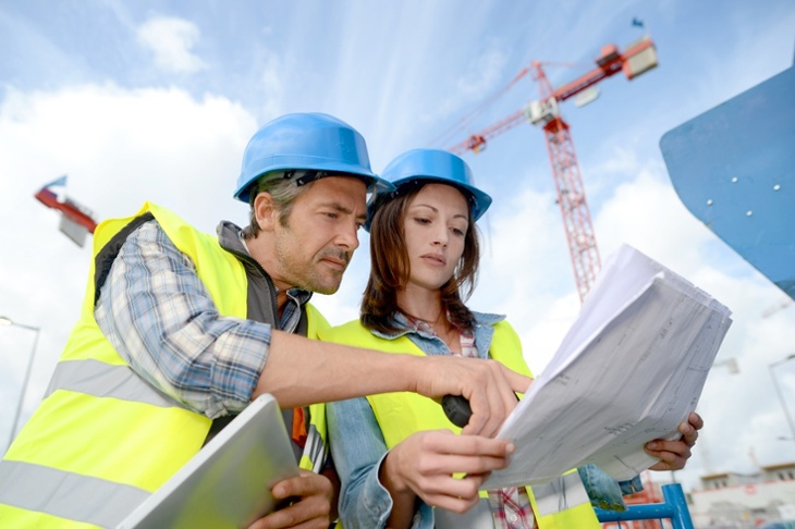 Man and woman in hard hats looking at construction plans
