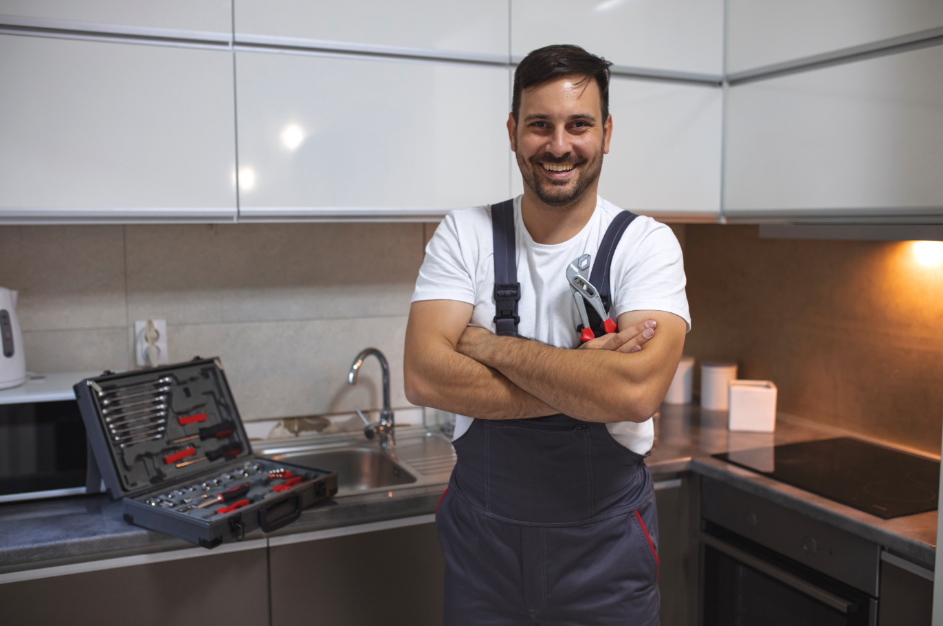 Smiling plumber with arms crossed in kitchen