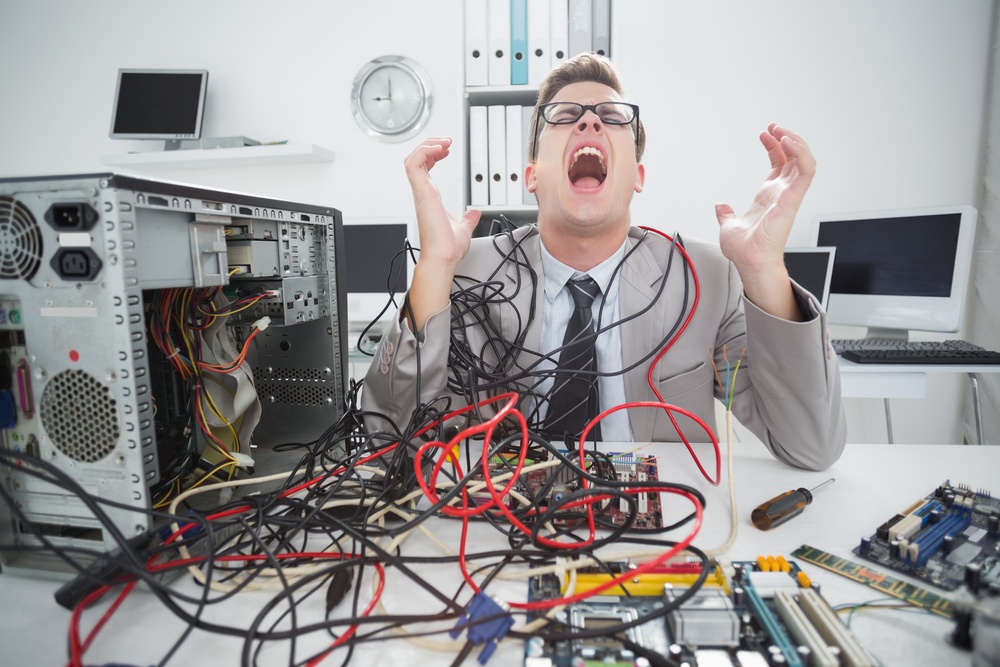 Stressed computer engineer working on broken cables in his office