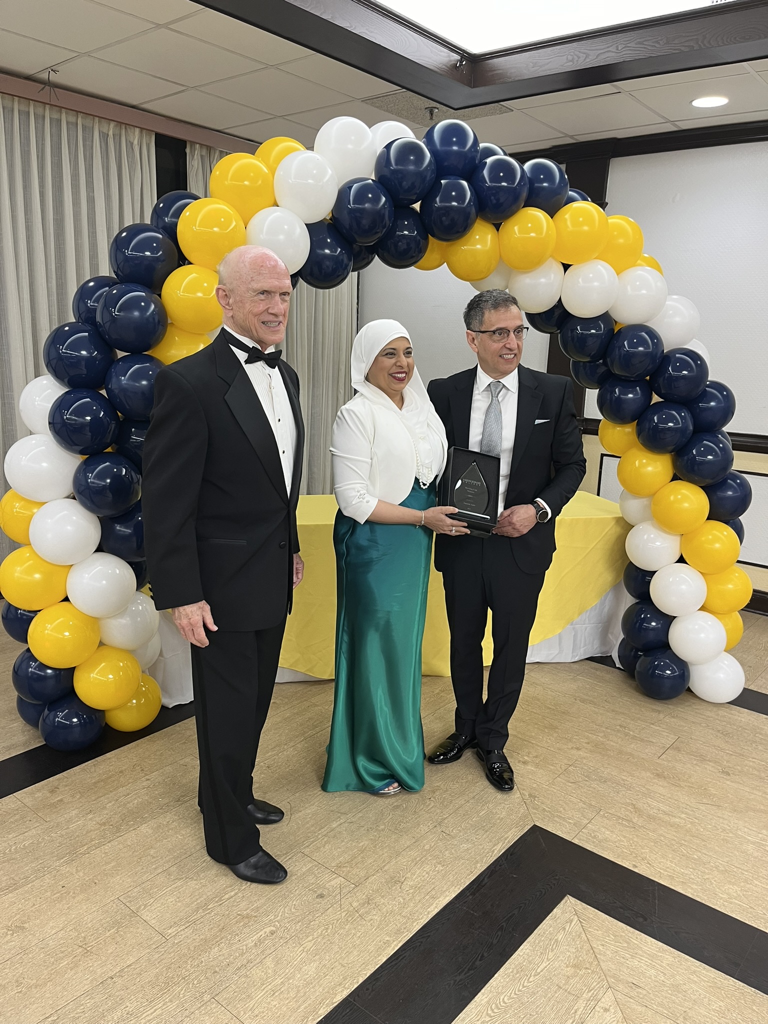 Woman posing with two men while receiving award