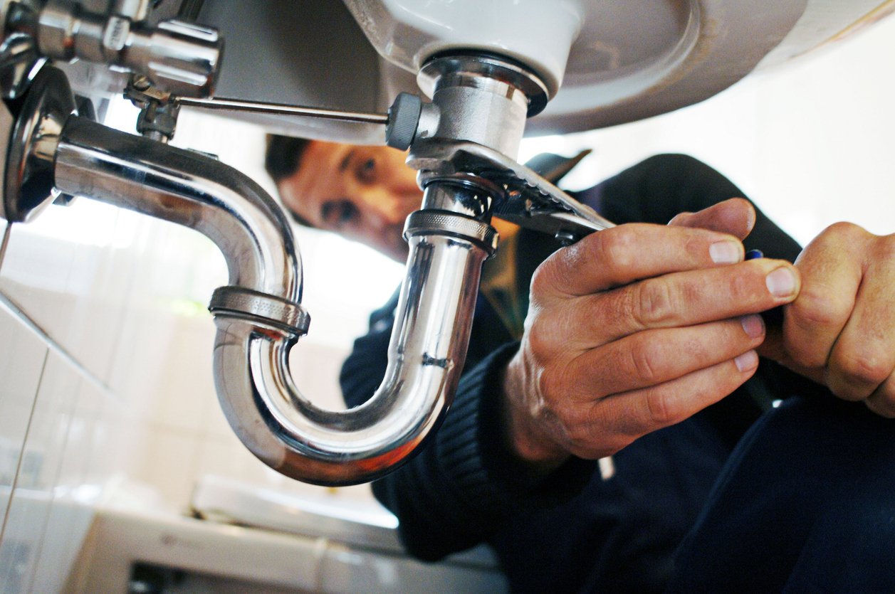 Close-up of plumber repairing sink with tool
