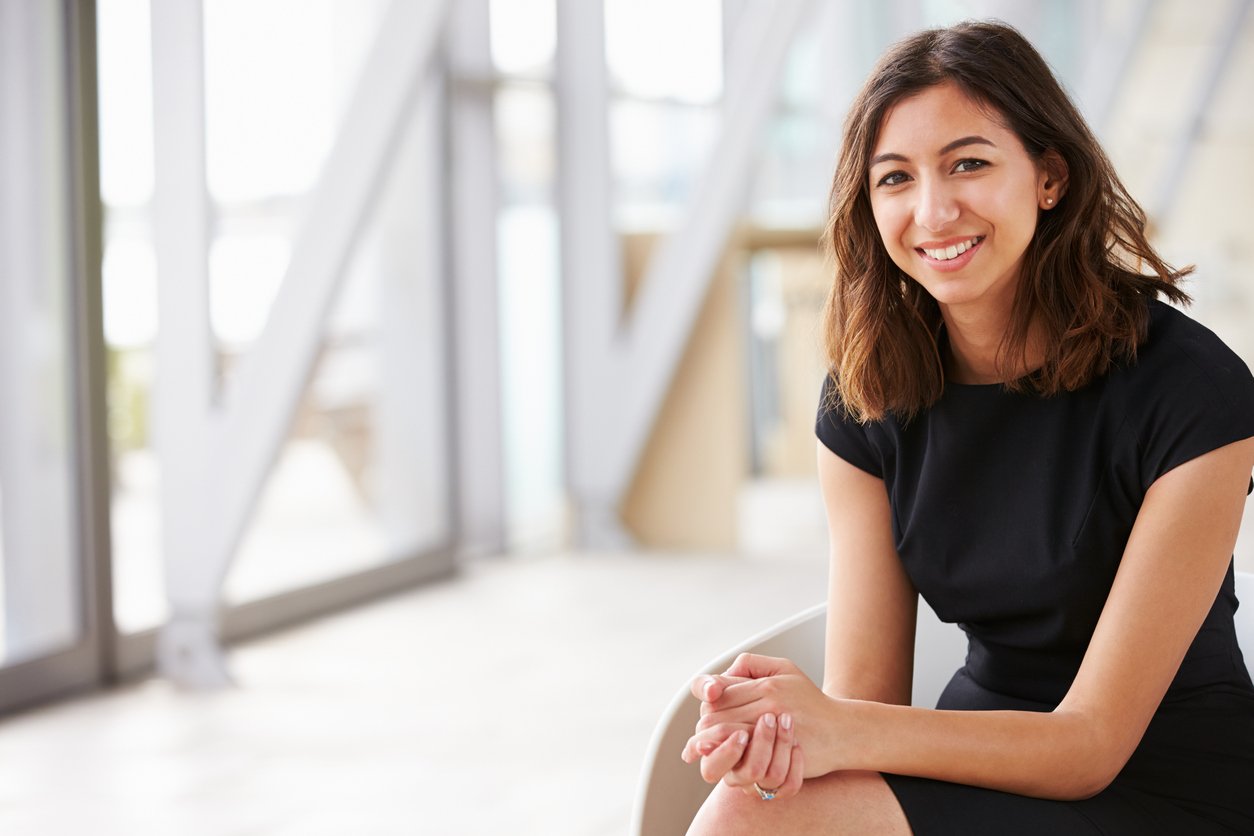 Smiling woman sitting with hands clasped