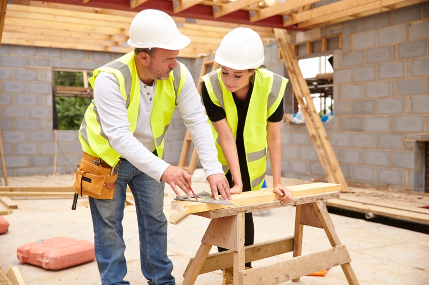 Carpenter with female apprentice working on building site