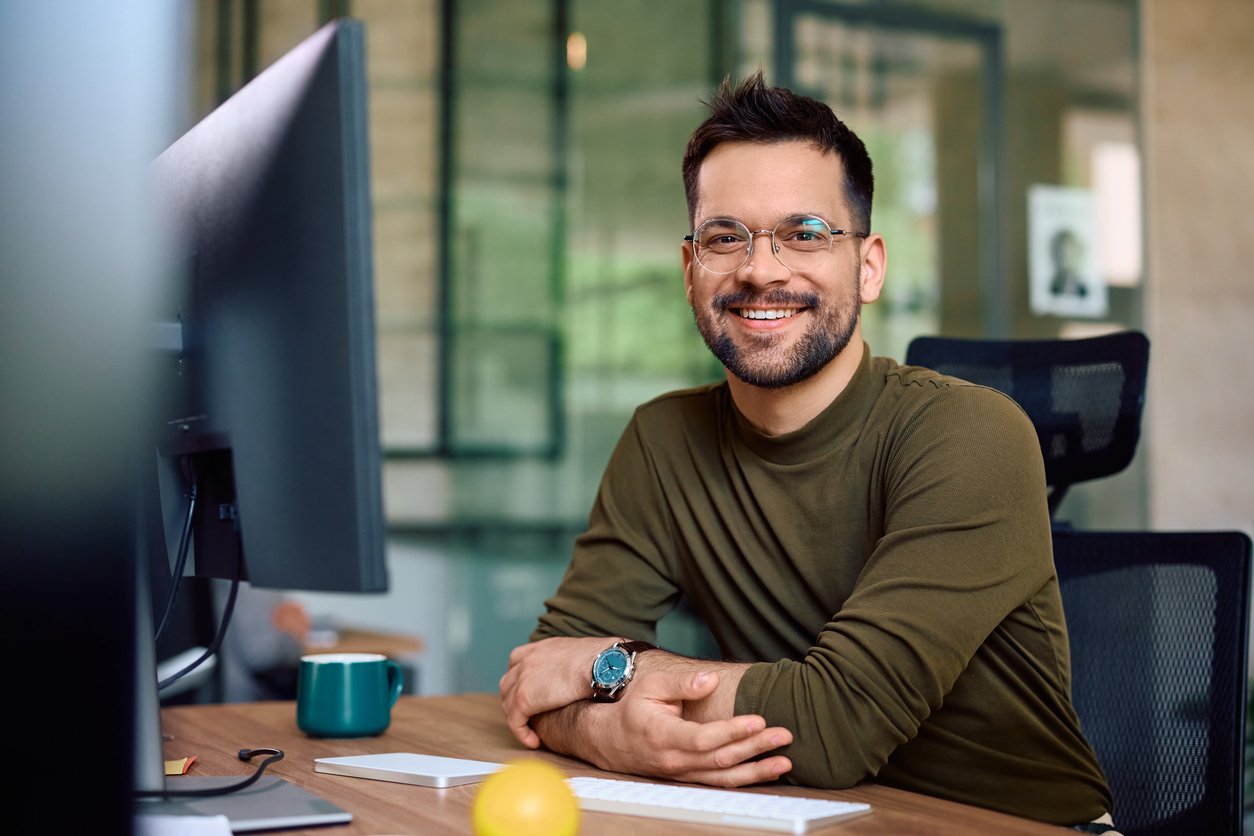 IT professional at his office desk looking at camera