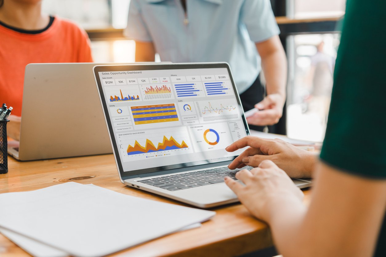 Person sitting in front of laptop displaying digital sales dashboard