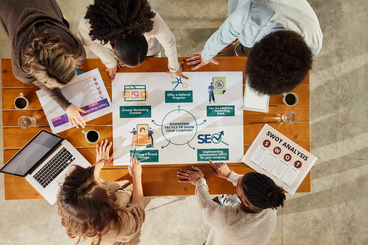 Vue aérienne d'un groupe de personnes à une table travaillant sur des stratégies de marketing numérique