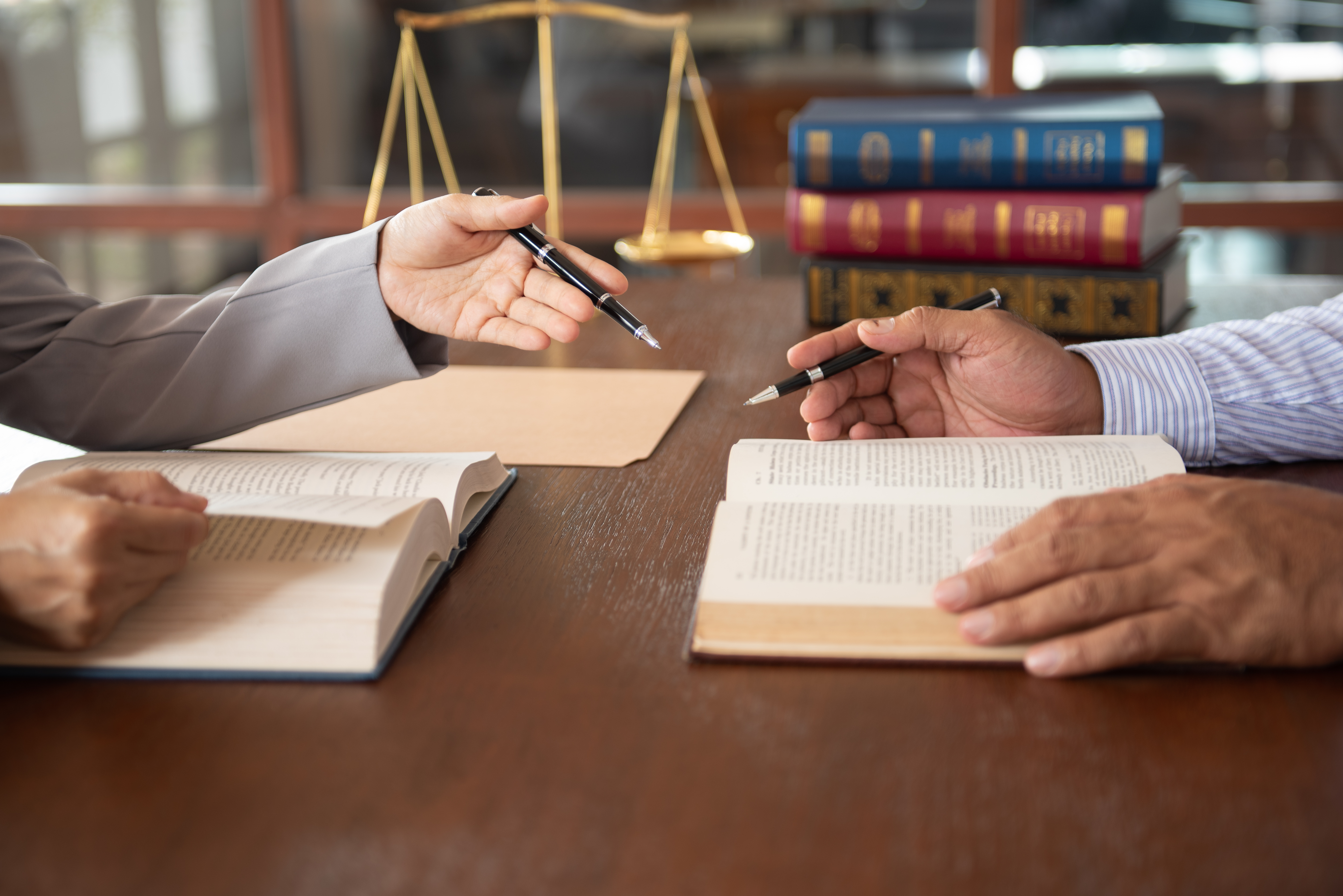  Legal professionals at a table with books and the scales of justice