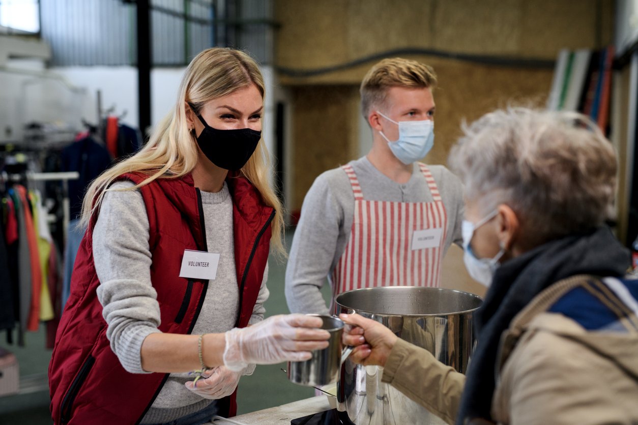 Masked woman serving food to a client