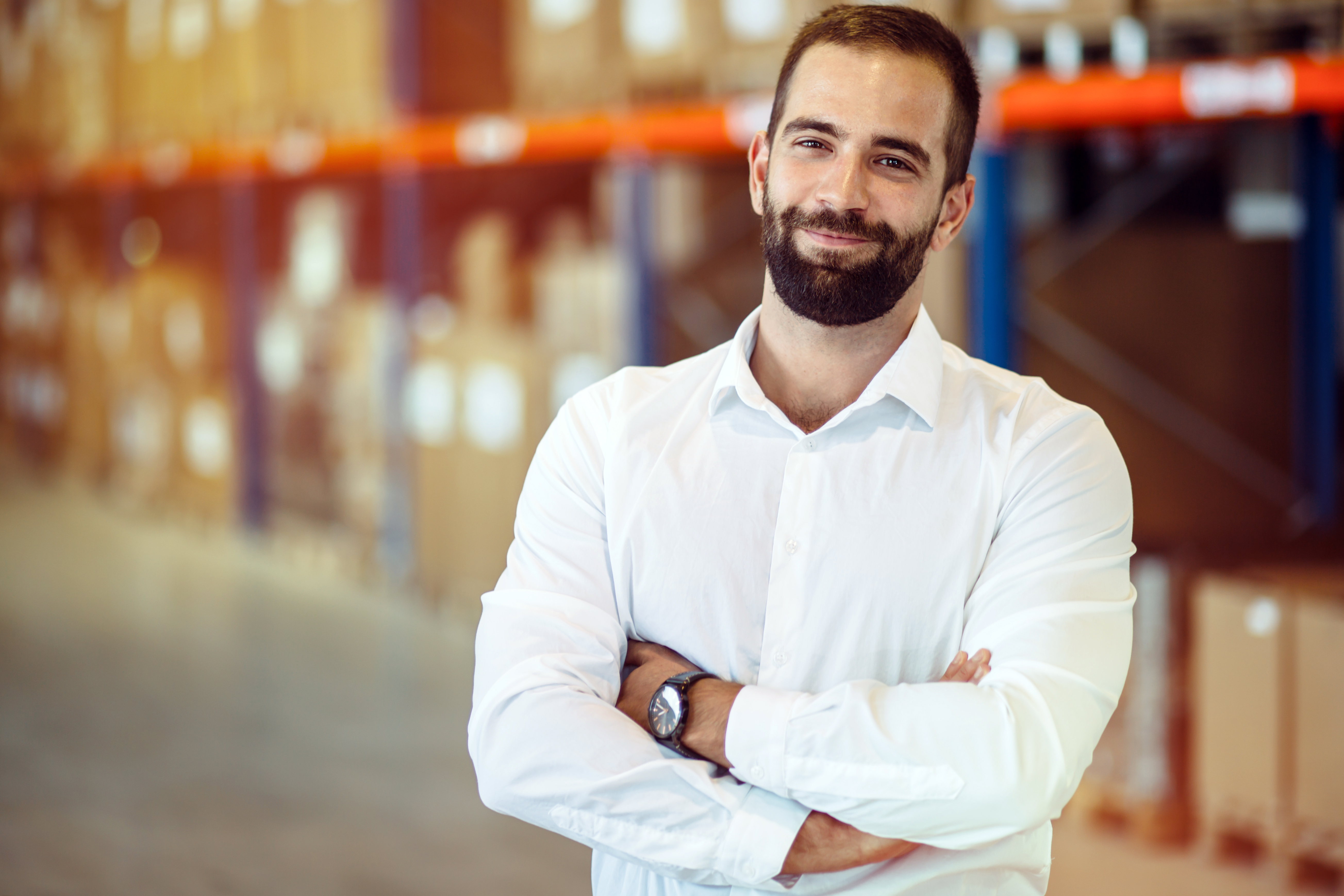 Logistics manager in warehouse standing with arms crossed
