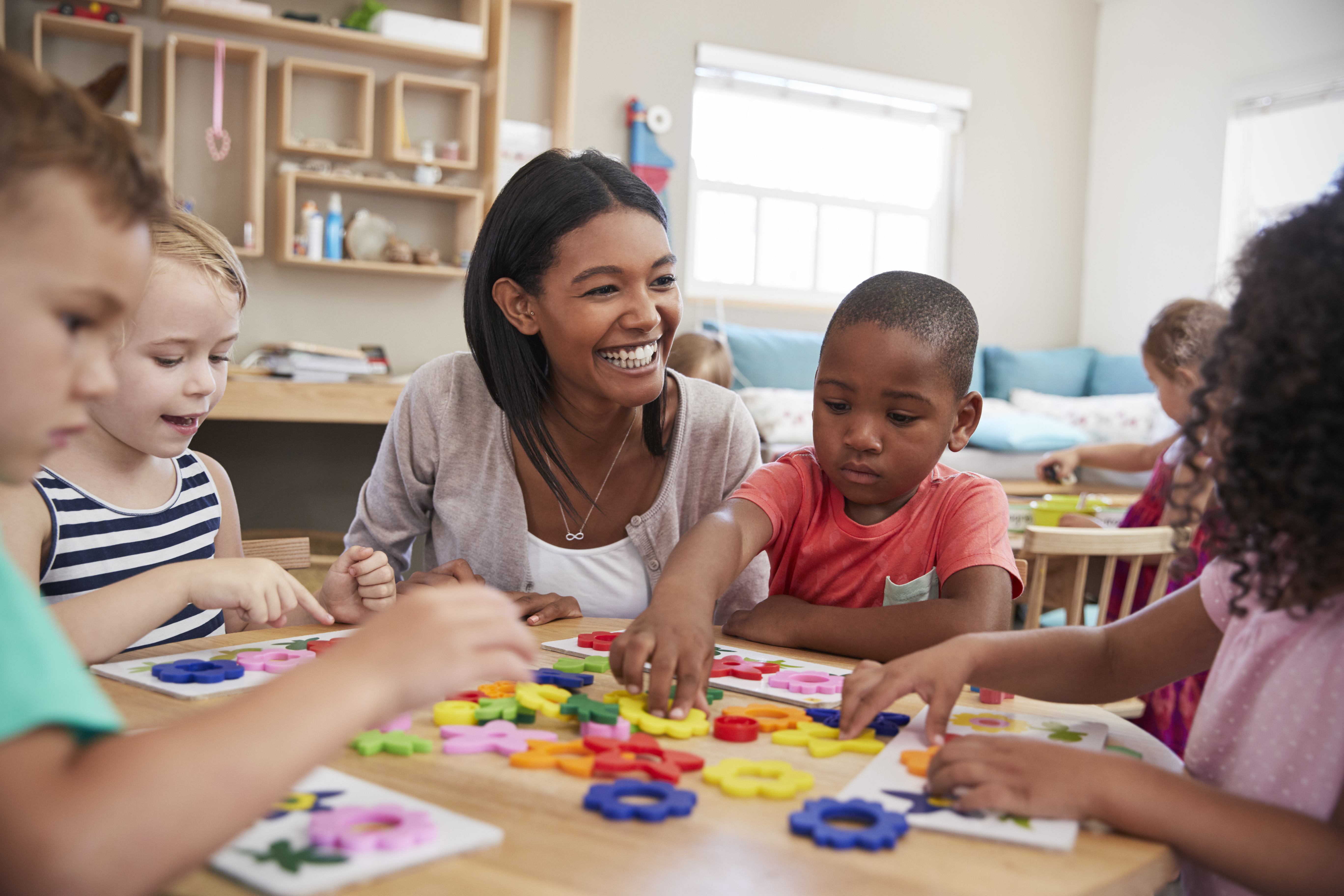 Smiling woman helping young children with an activity