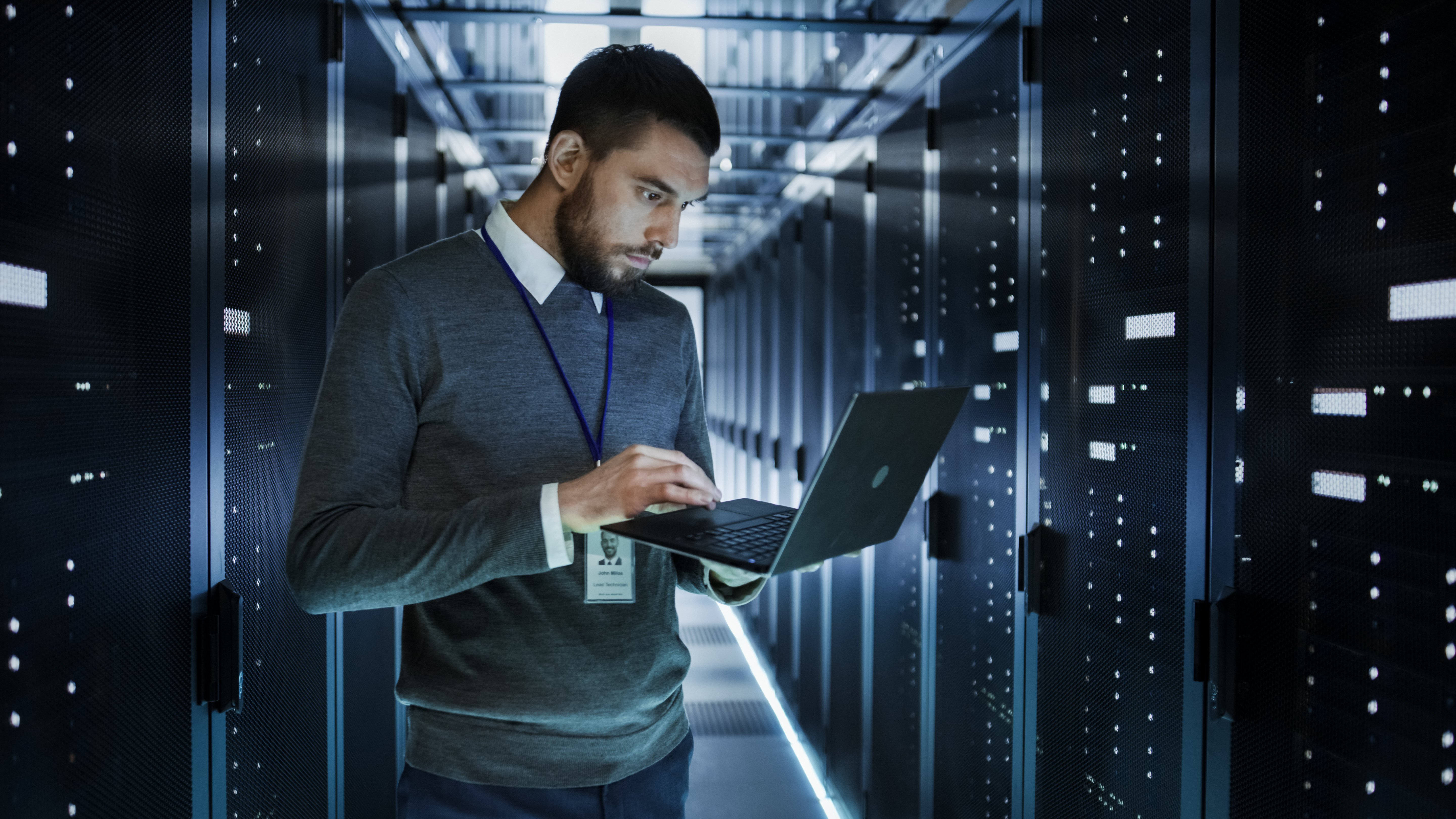 Network administrator holding laptop while standing in data centre