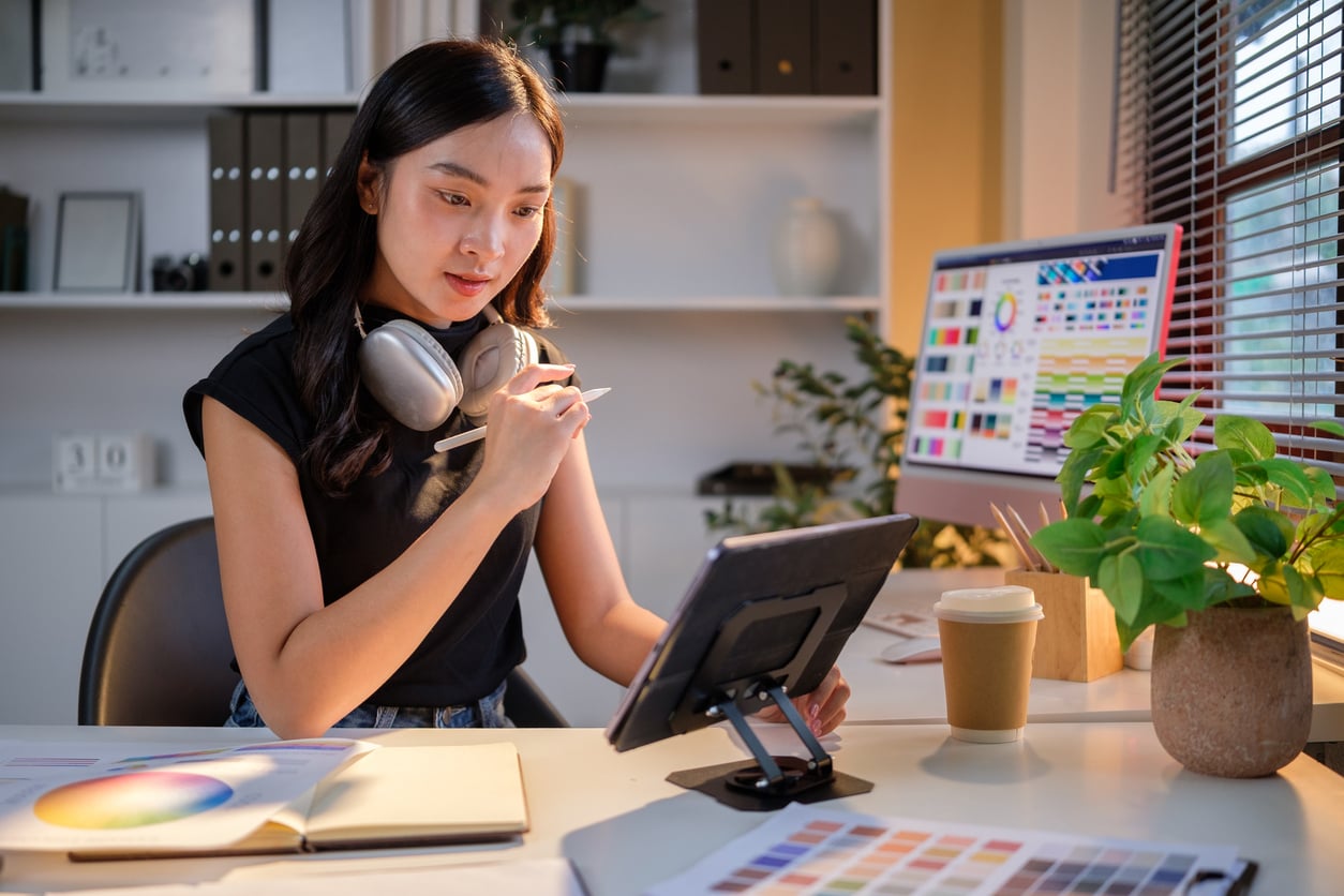 Designer working on tablet surrounded by colour charts