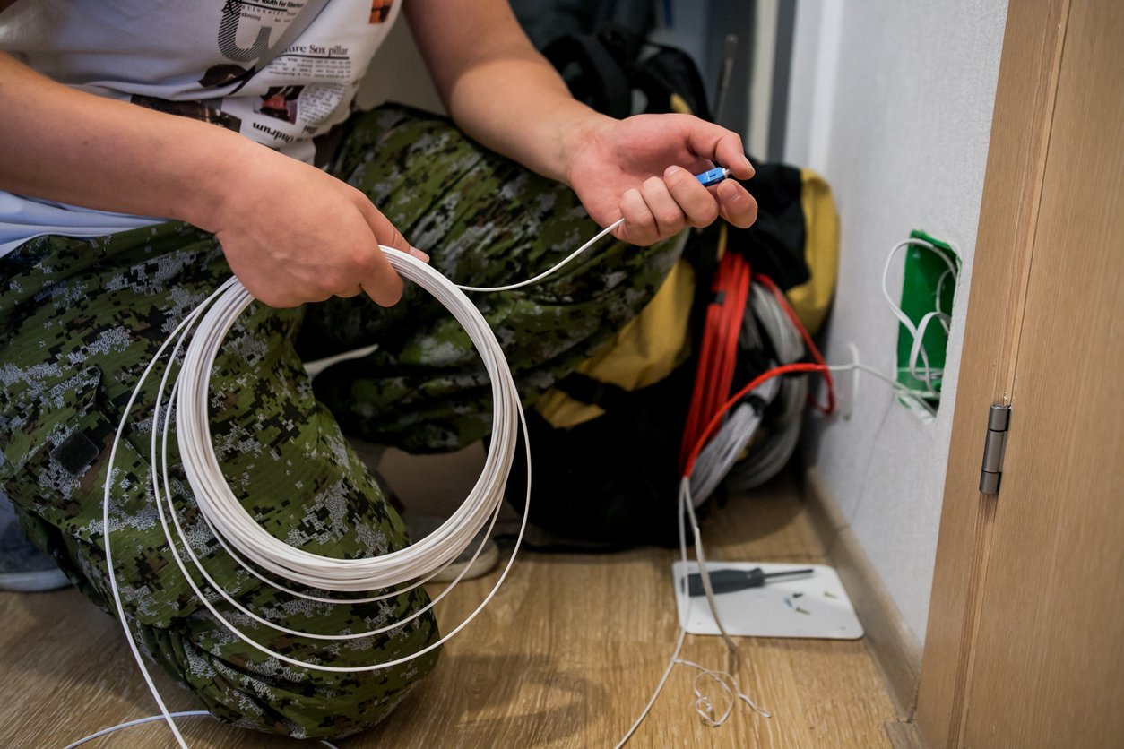 Technician installing fibre optic wire at a house
