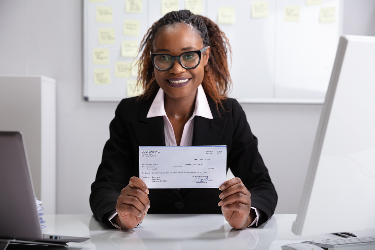 Woman sitting at a desk holding a cheque