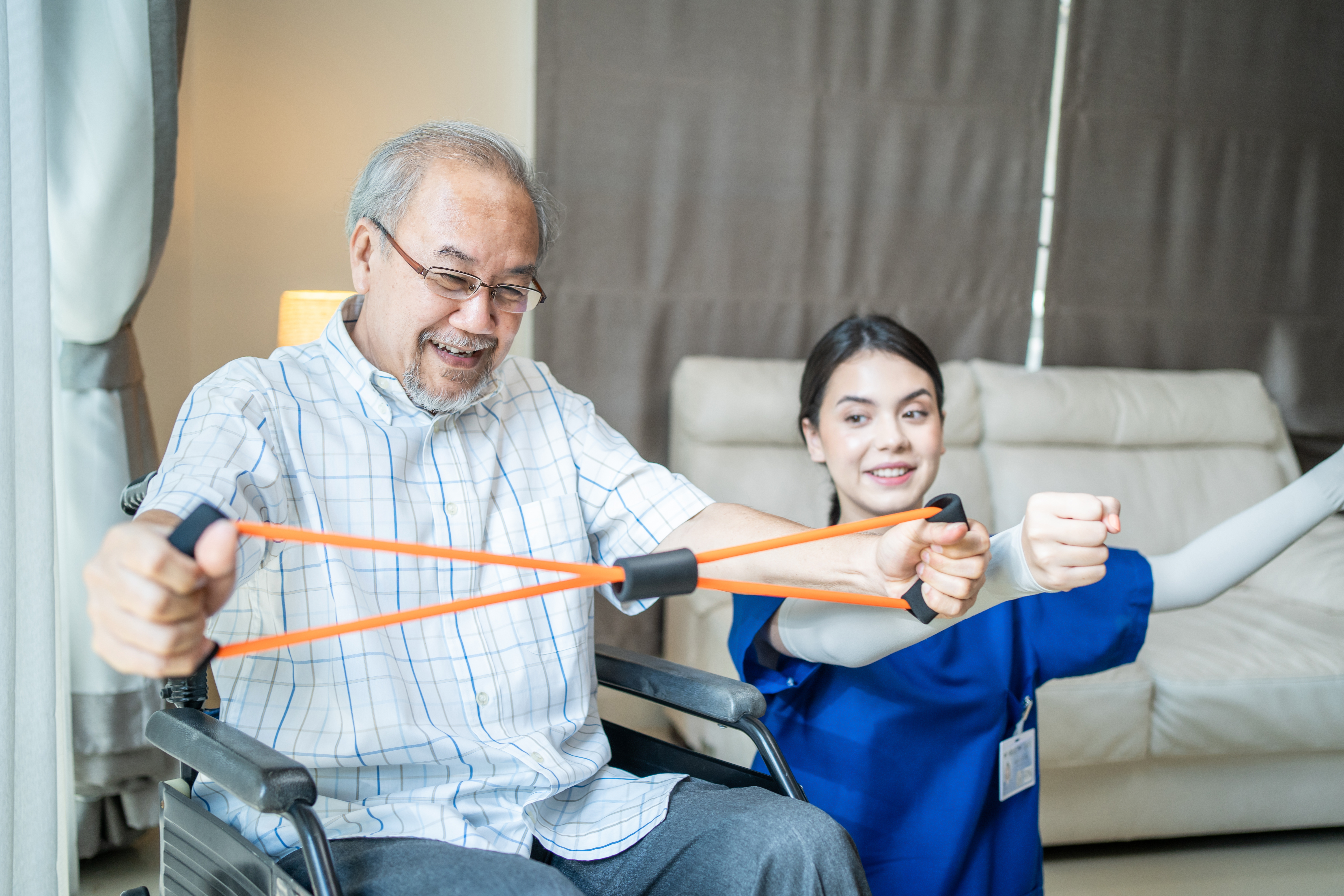 Physiotherapist assistant helping man in wheelchair use resistance bands