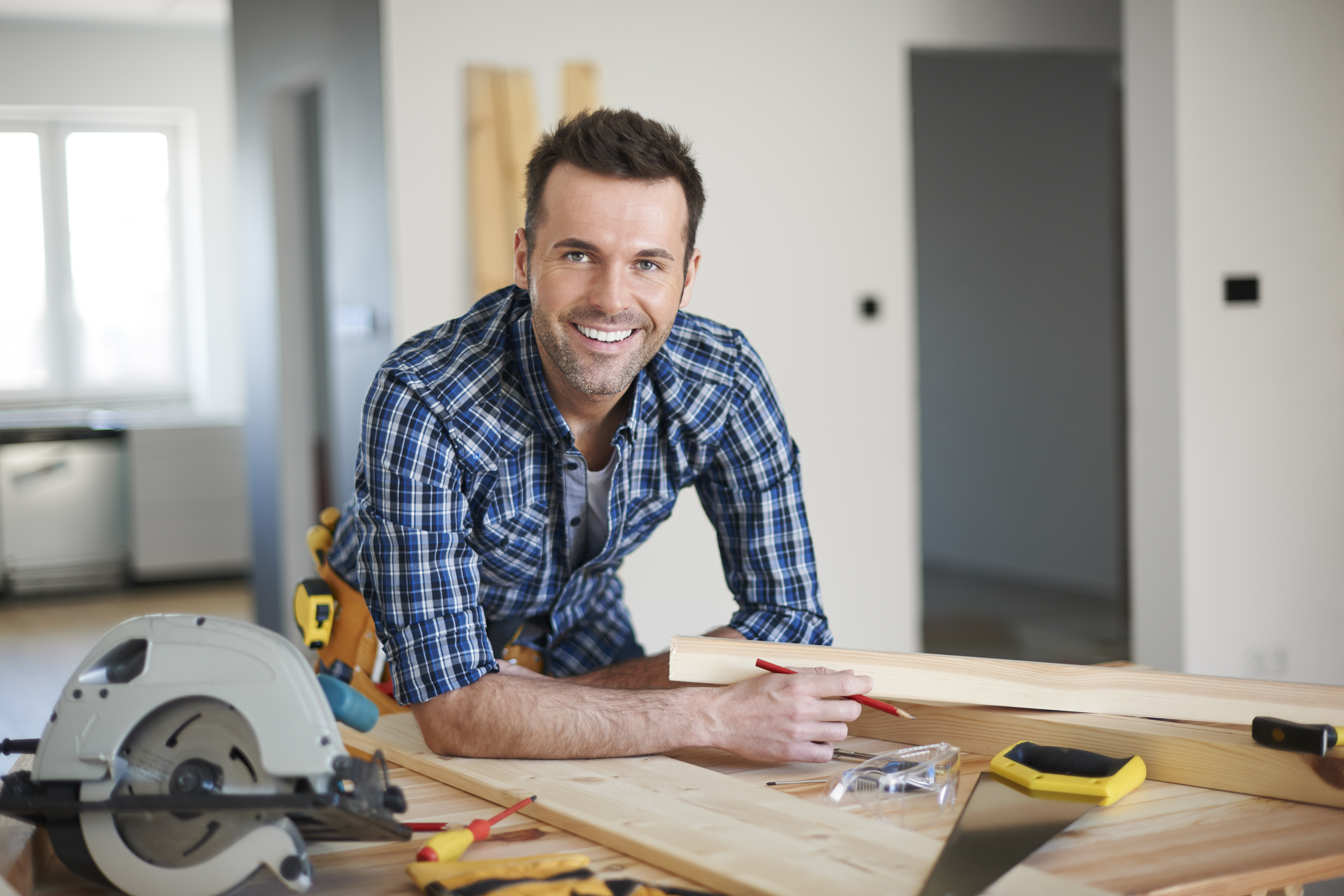 Smiling carpenter leaning on workbench