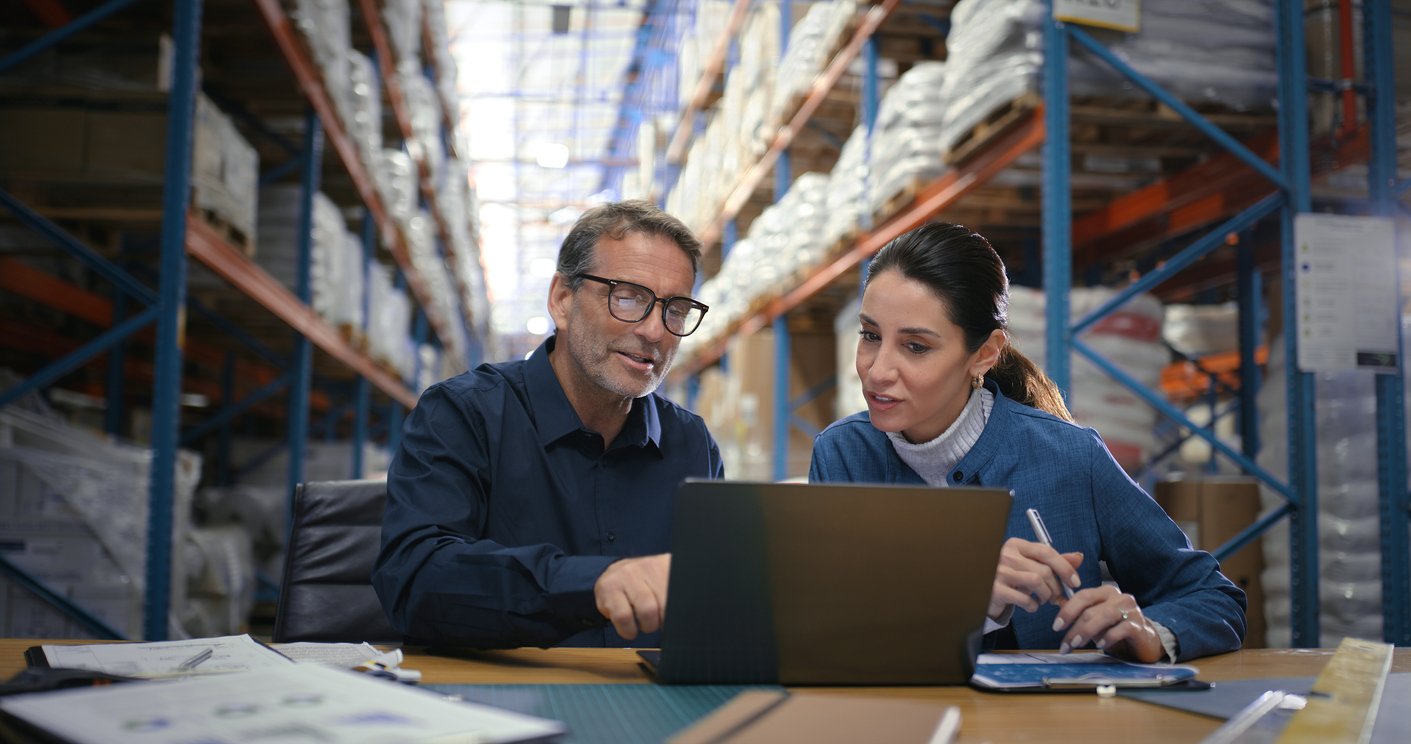 Two people looking at laptop in warehouse