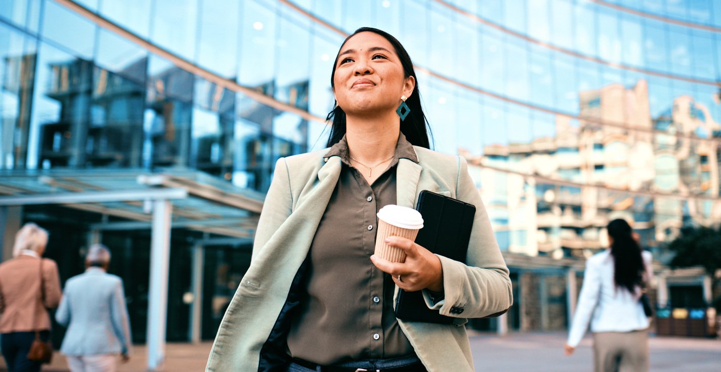 Confident businesswoman walking with coffee outside office building