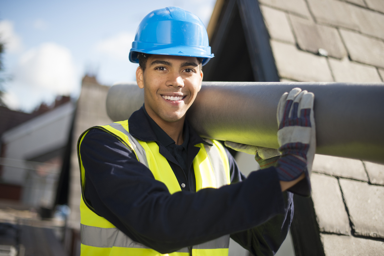Construction worker carrying pipe