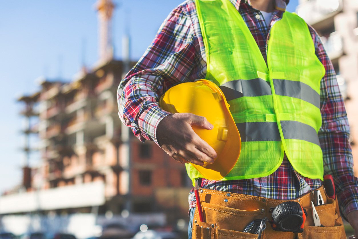 Construction worker holding helmet at building site