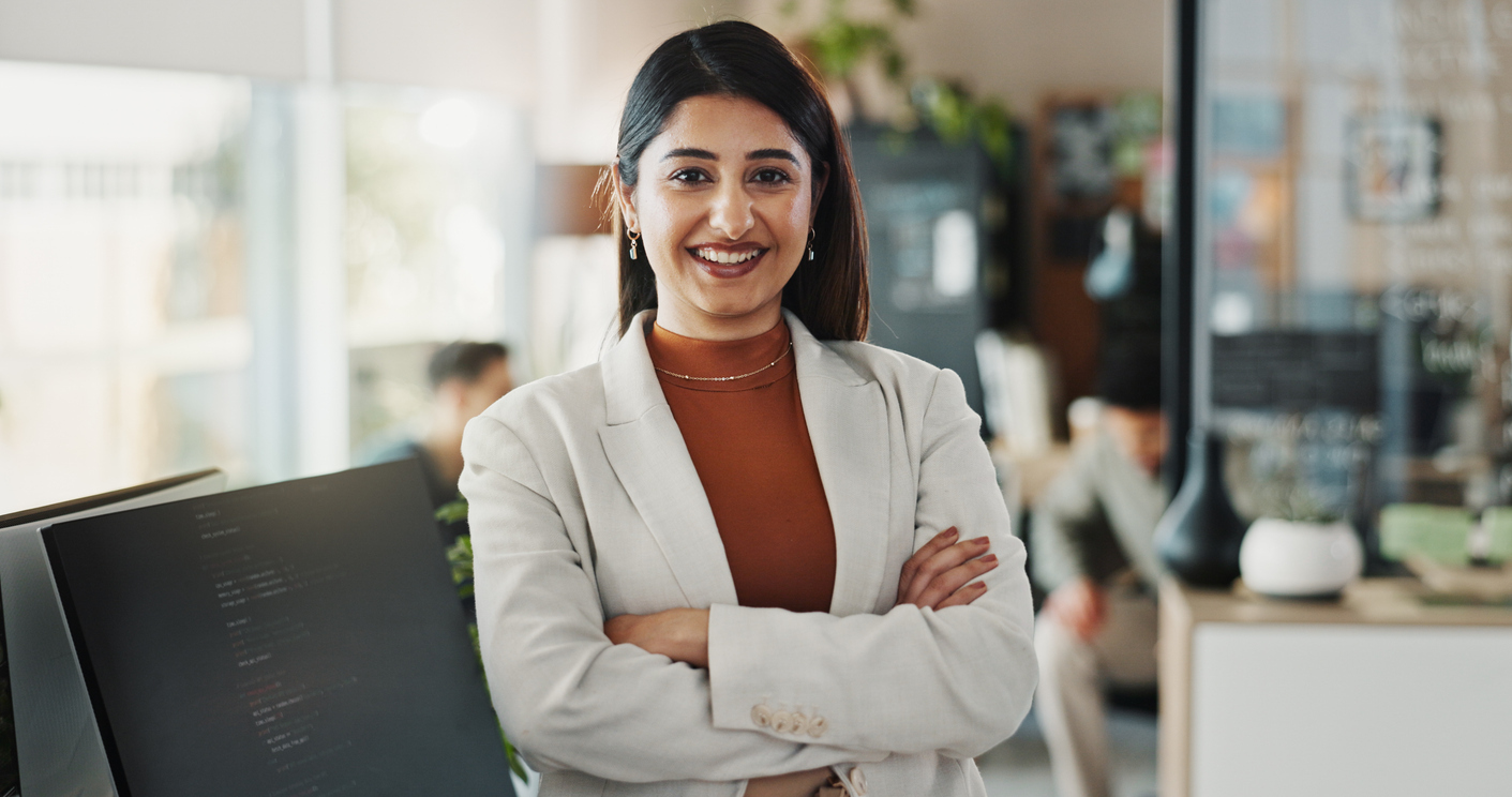 Smiling legal assistant standing in office with arms crossed