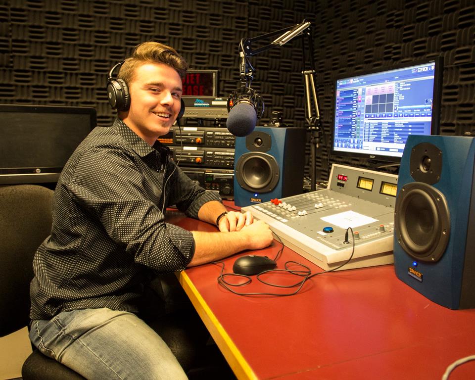 A radio student sitting at a studio console